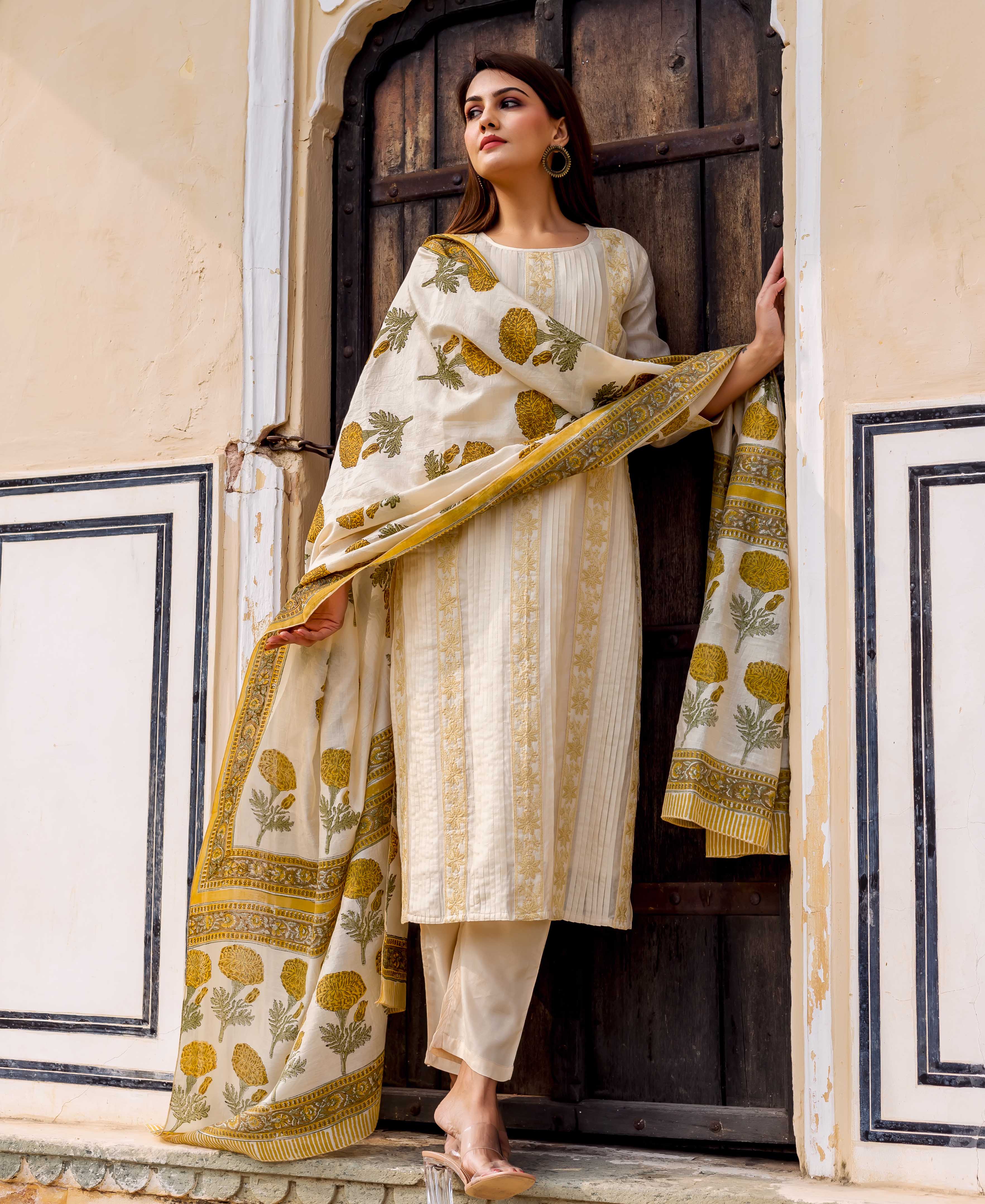 Model wears cream embroidered kurta set with yellow floral hand block printed dupatta.