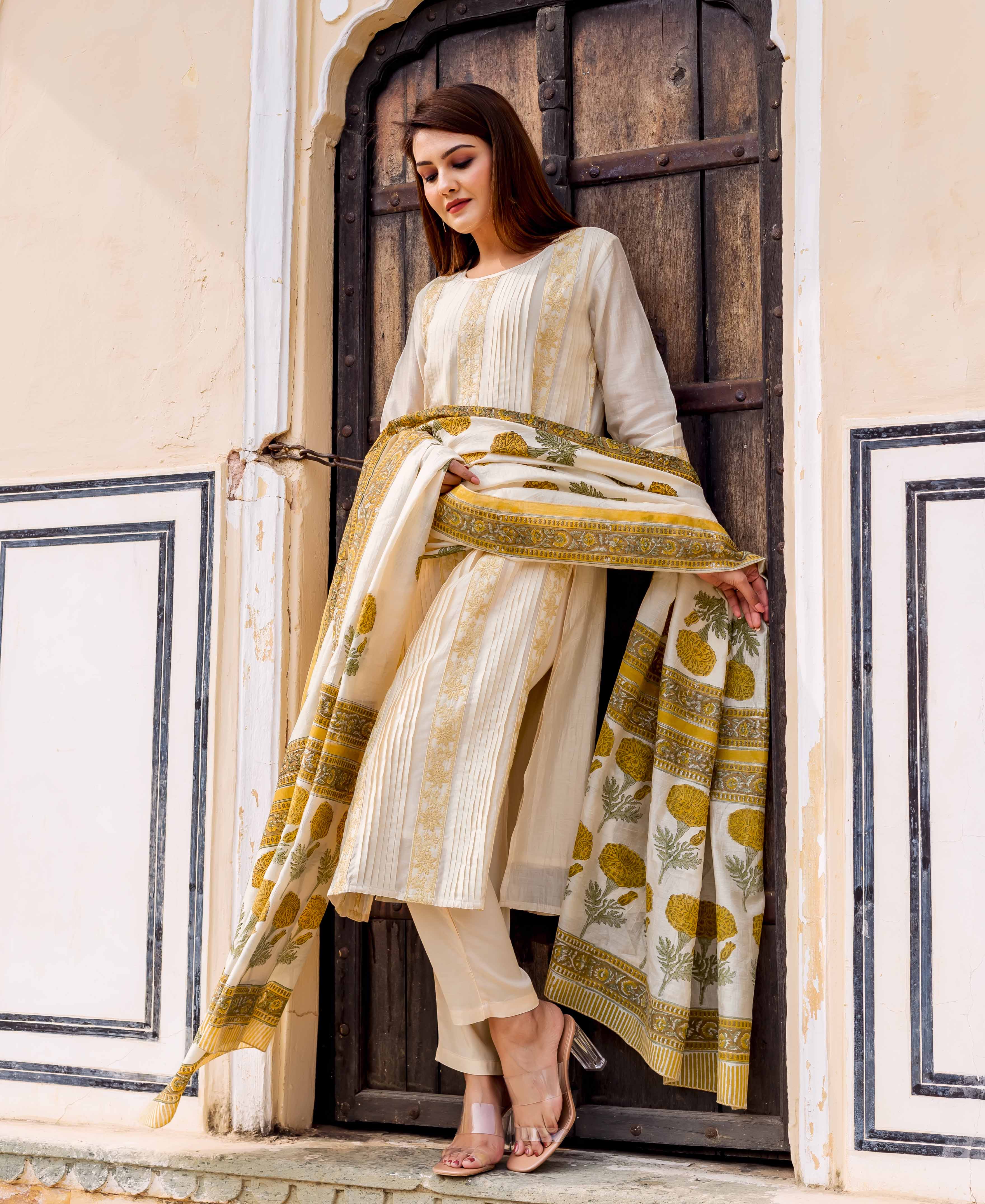 Model wearing an off-white embroidered kurta set with yellow floral hand block prints.