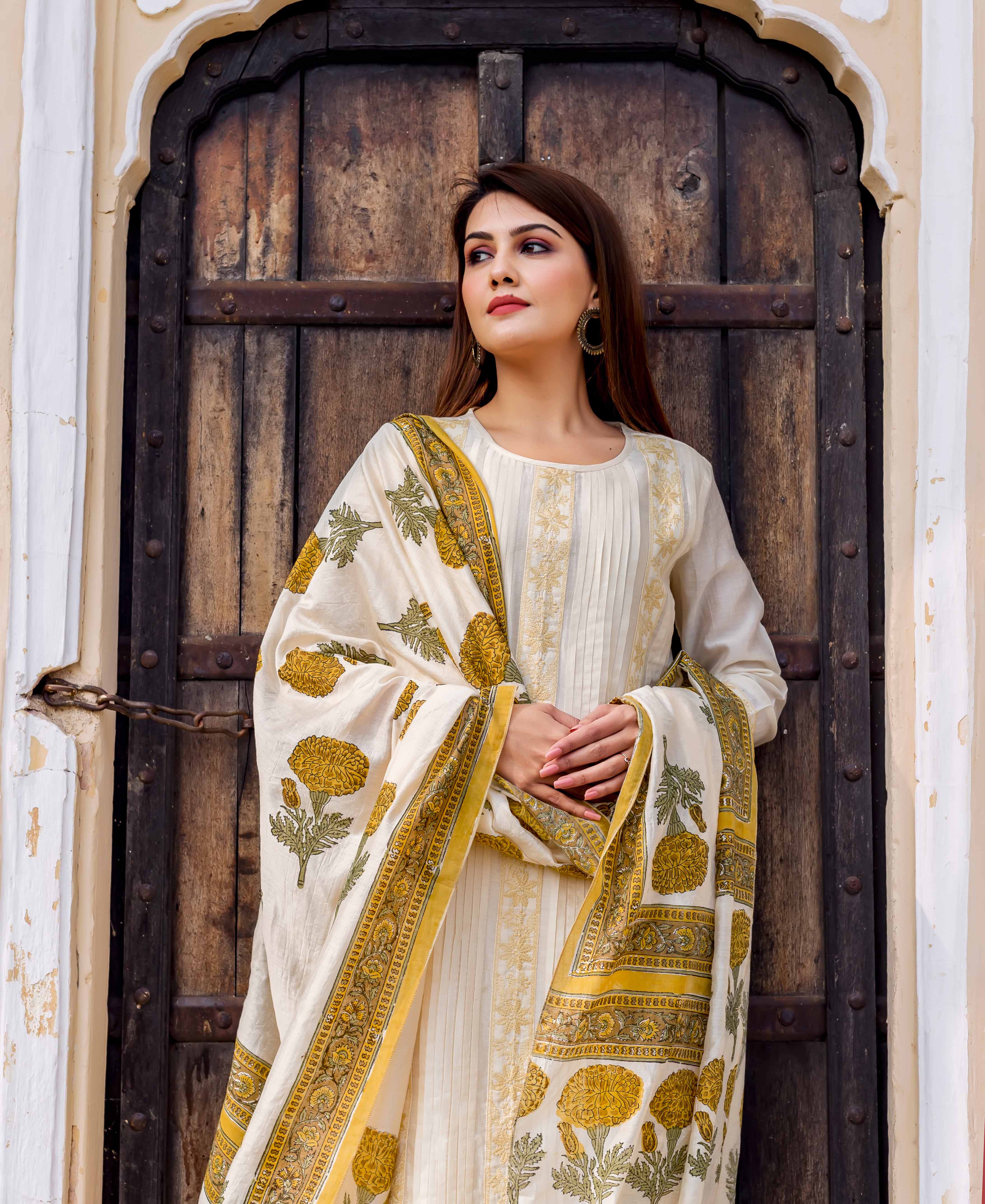 Woman in cream embroidered straight kurta with yellow-green marigold block print dupatta.
