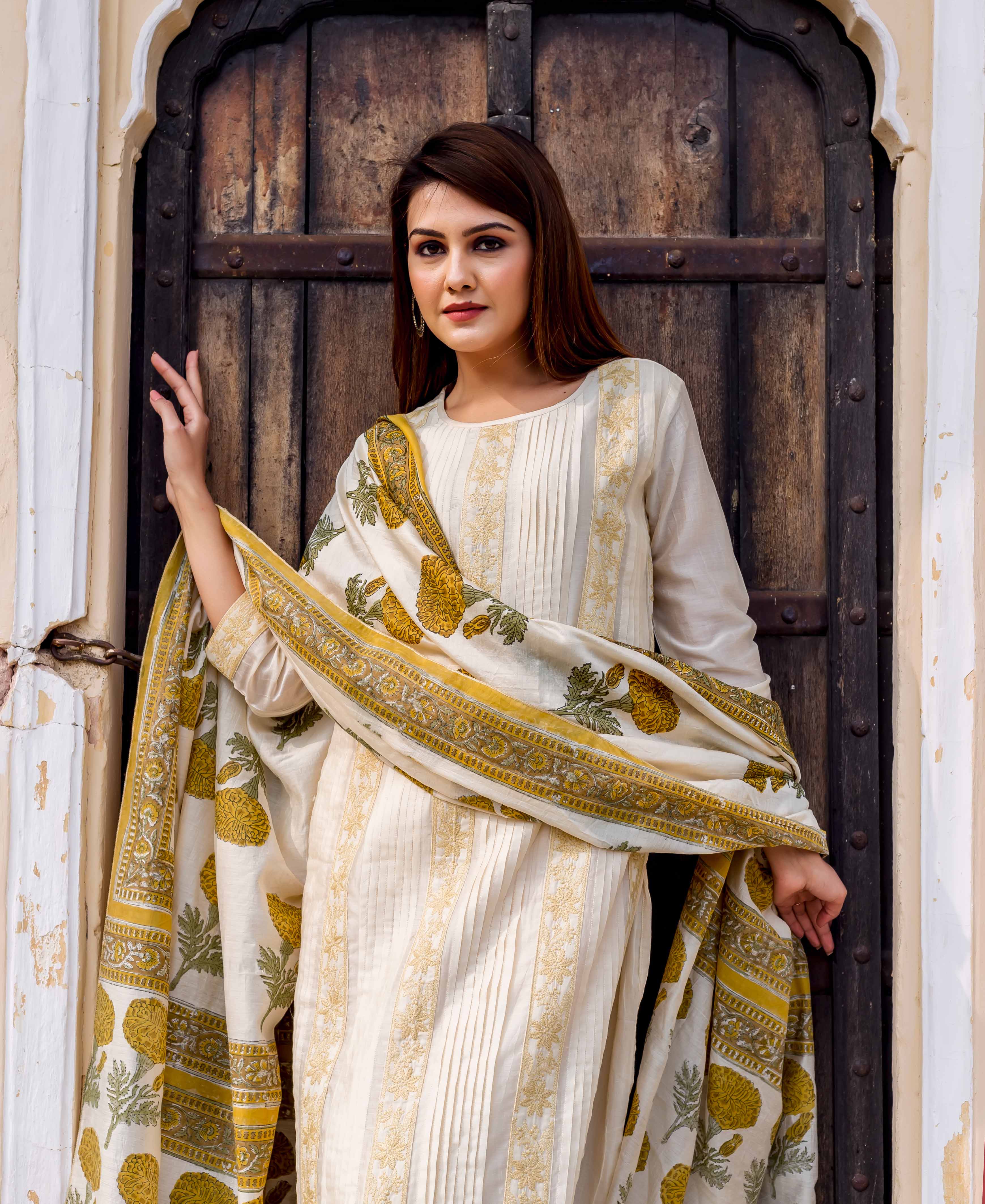 Model in off-white hand block printed and embroidered kurta with yellow floral dupatta.