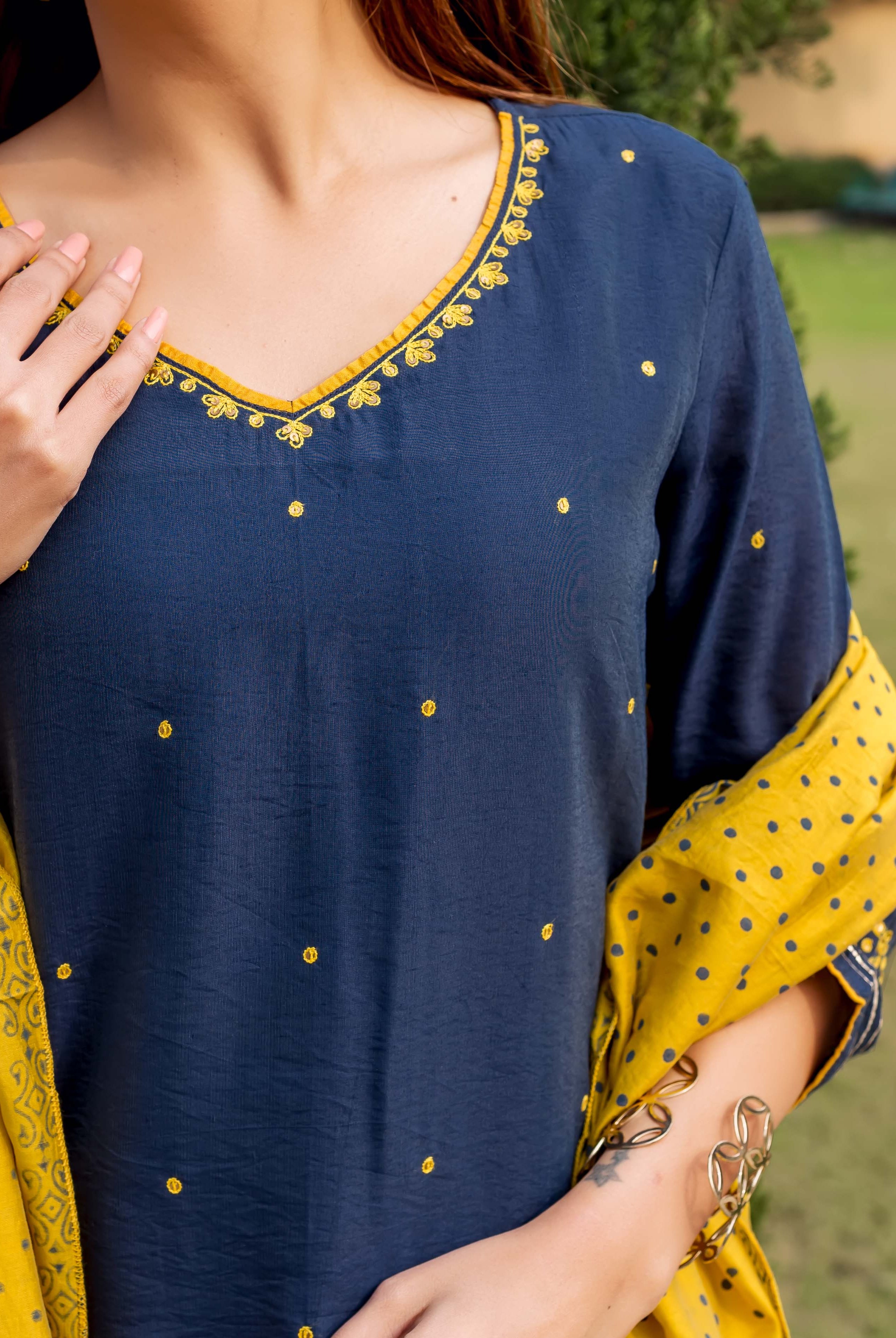 Model in navy blue kurta with yellow embroidered V-neck, dots, and yellow polka dot dupatta.