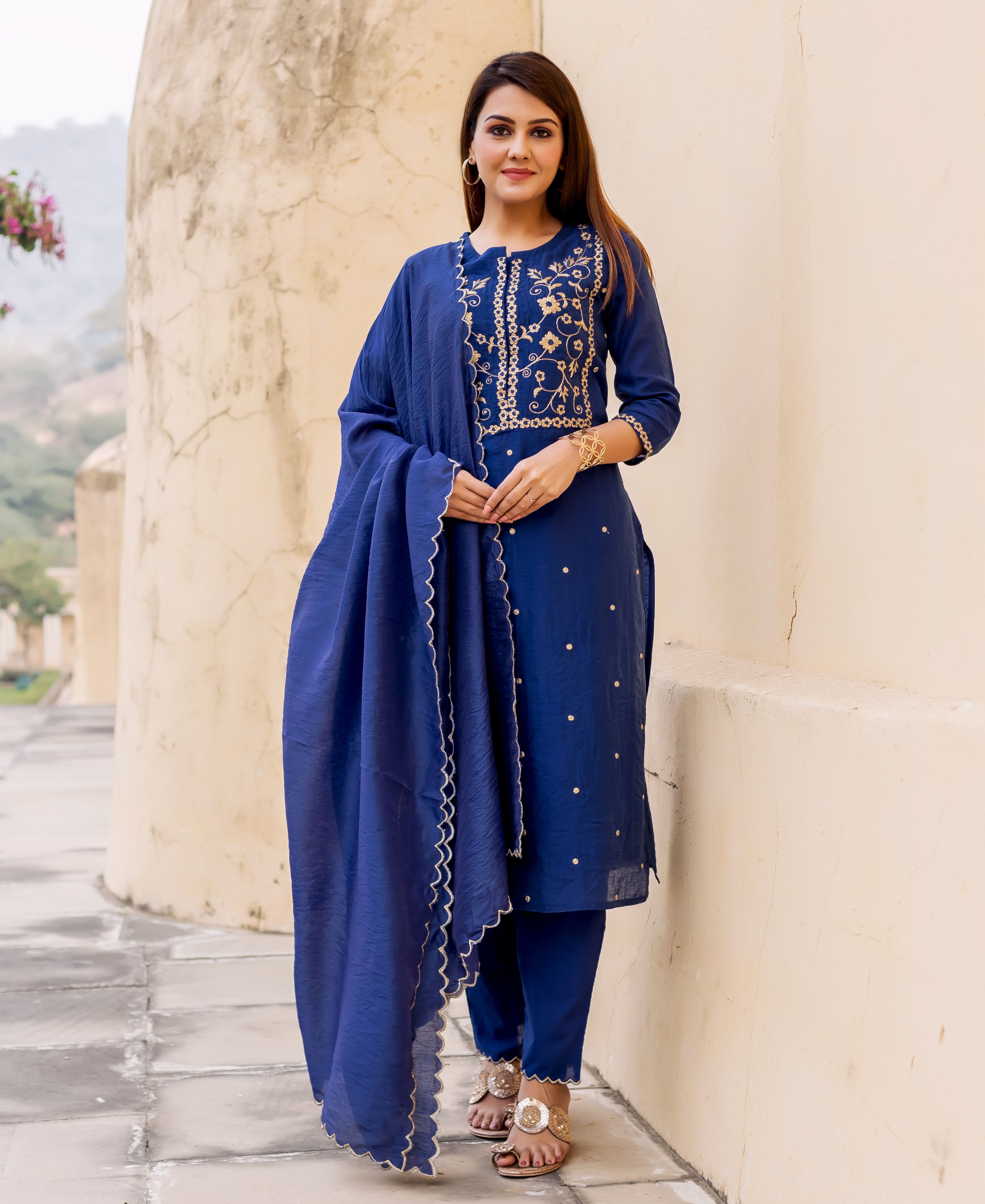 Woman wears midnight blue hand-embroidered kurta set with gold motifs and scalloped dupatta.