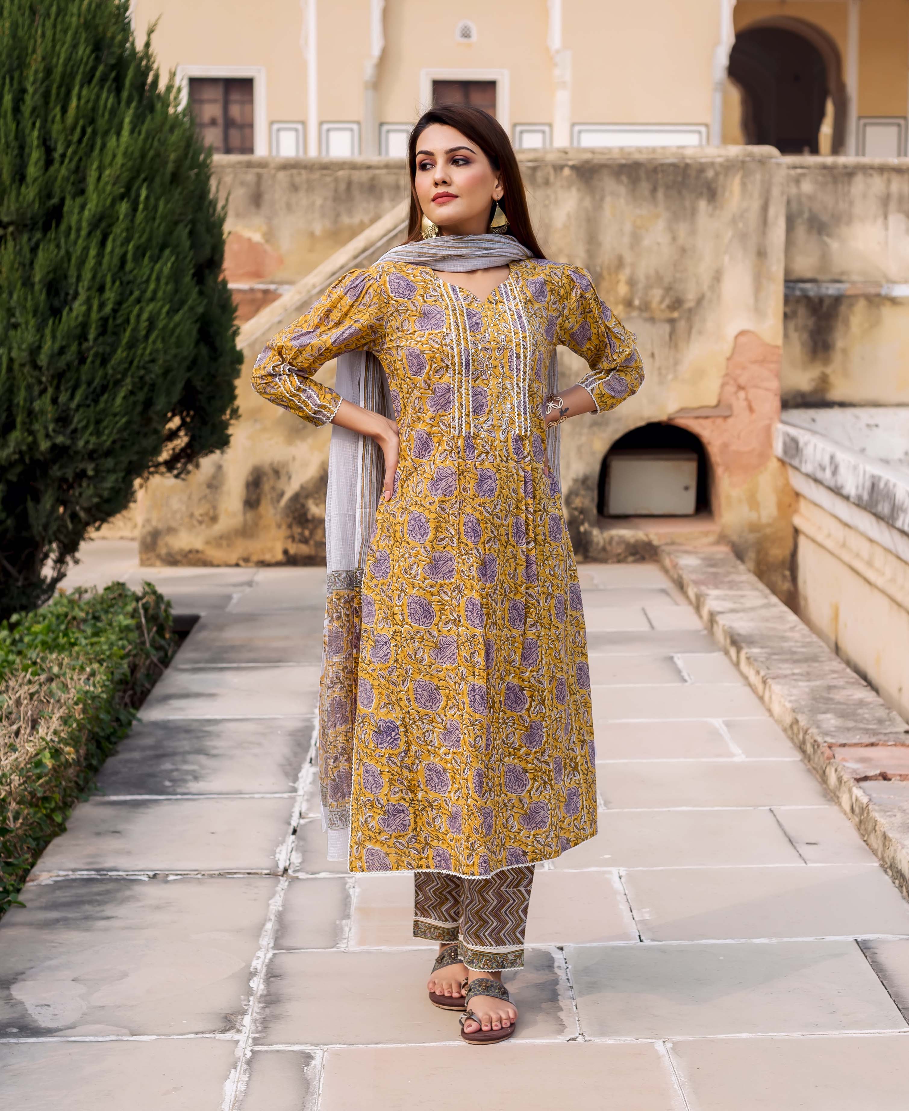 Model in yellow kurta with purple floral block print, grey dupatta, and patterned pants.