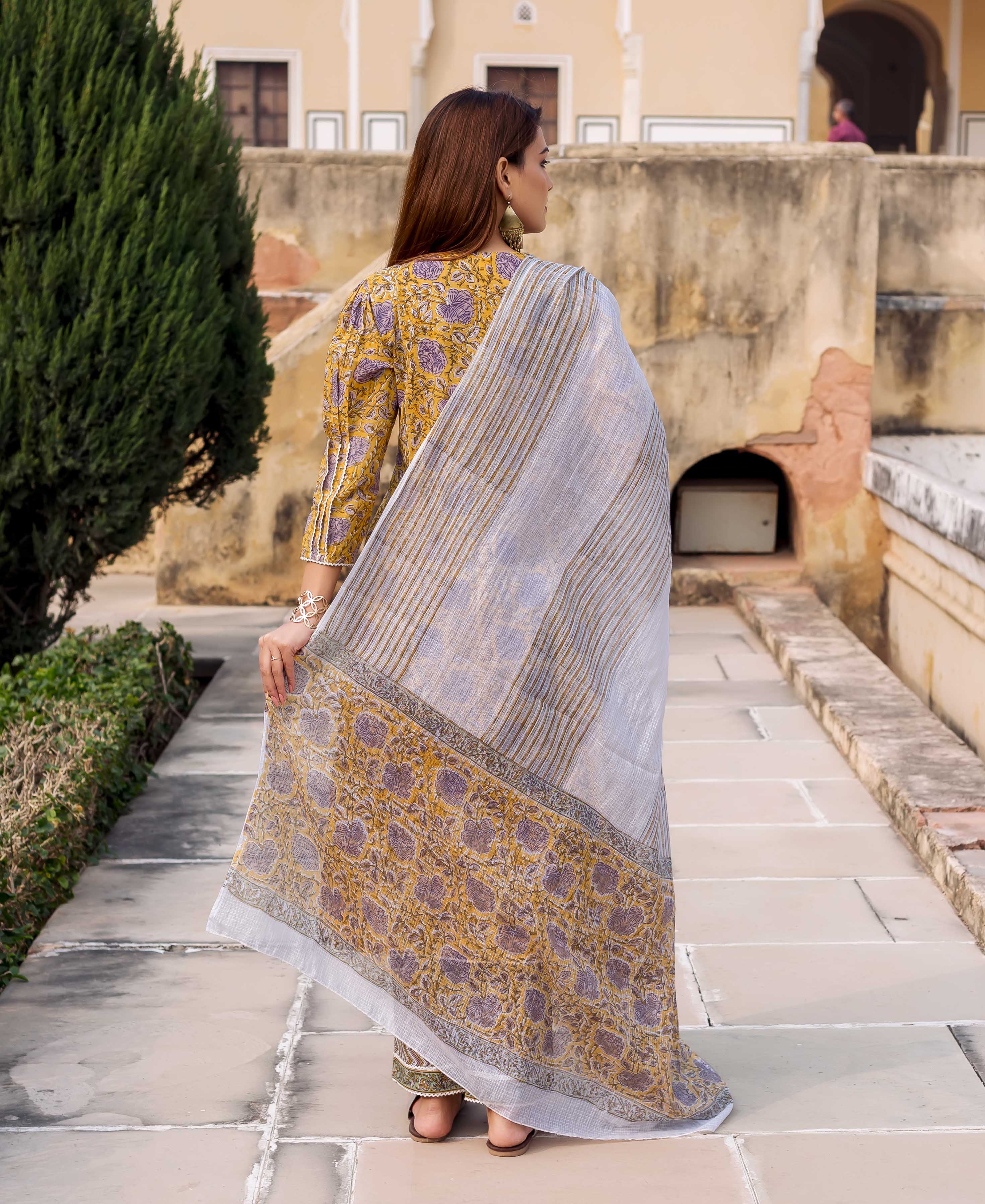 Rear view model in yellow floral block-printed straight kurta with grey striped dupatta.