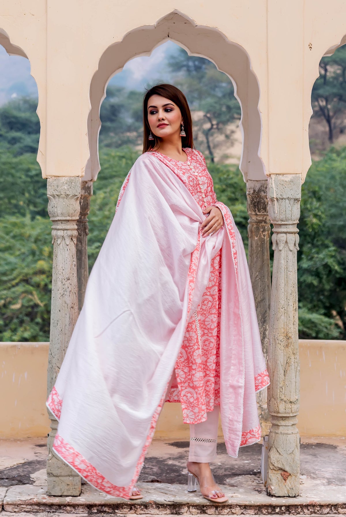 Full-body model wears a peach and white hand block printed kurta, white pants, and pink dupatta.