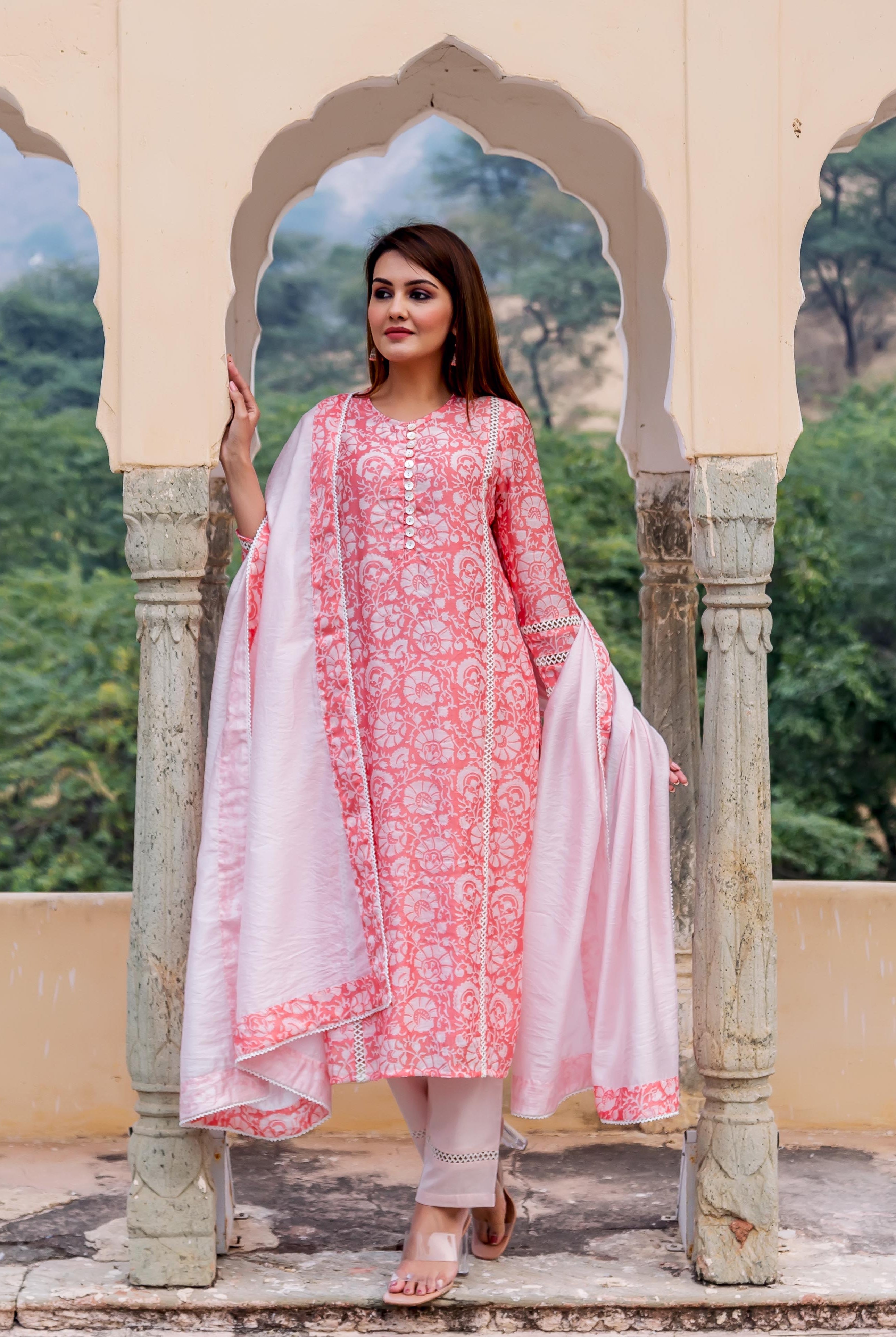 Model standing in a peach and white hand-block printed floral kurta with delicate lace trim.