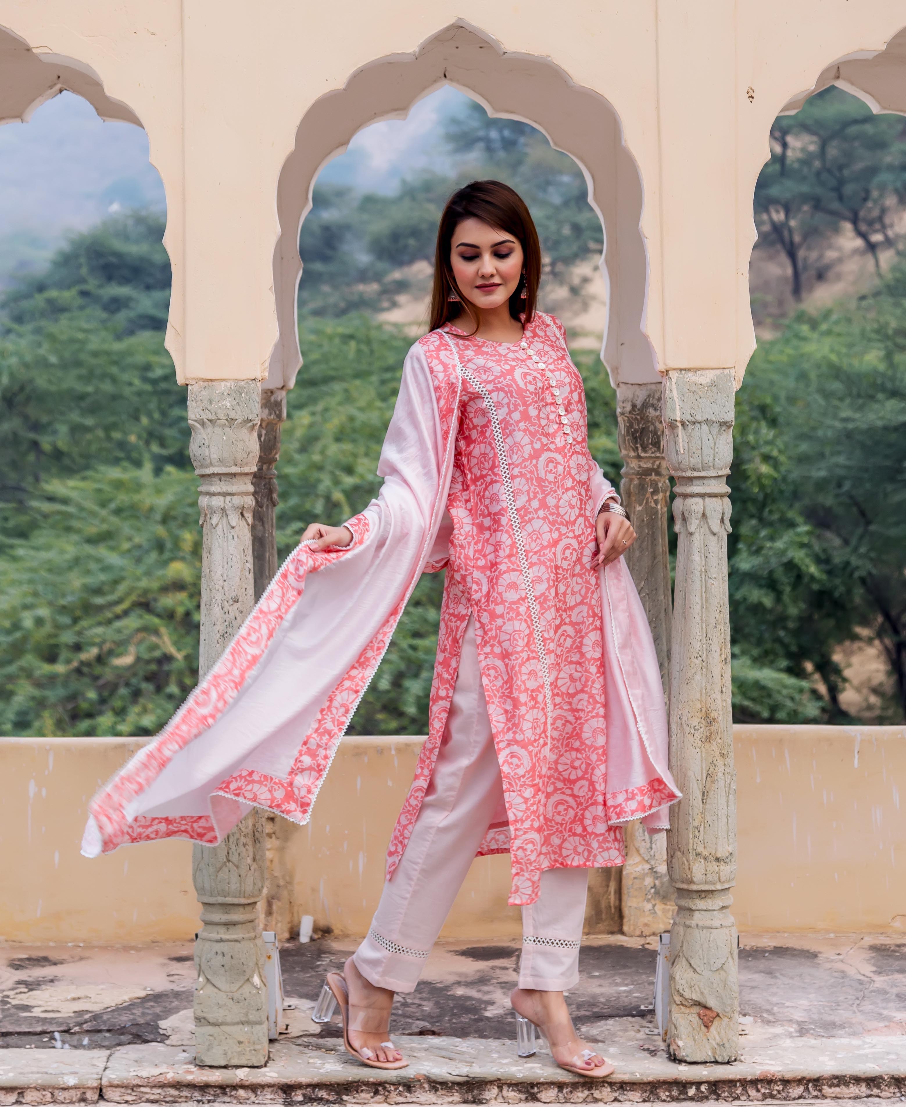 Woman wears a peach hand block printed kurta set with white pants and flowing dupatta.