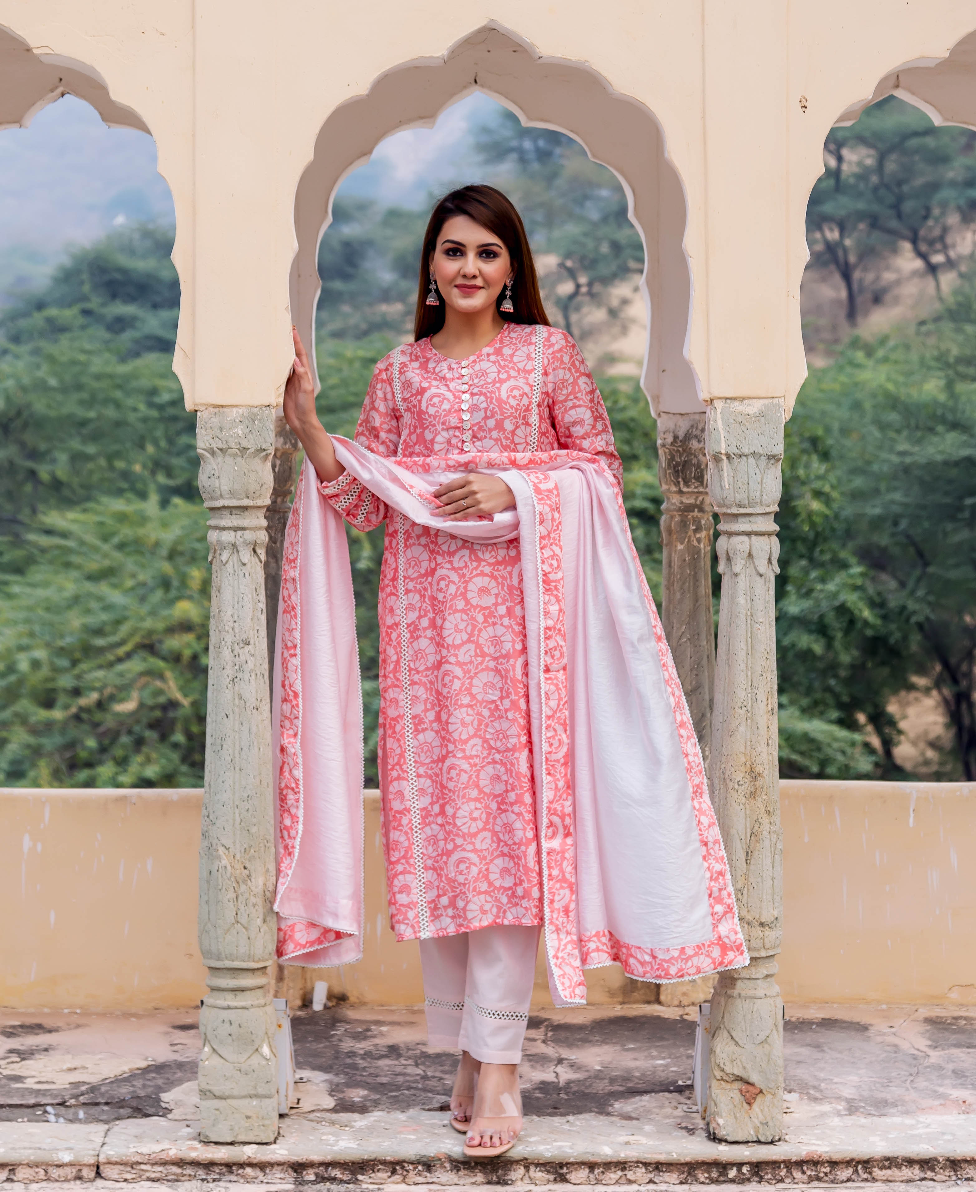 Full-length model in peach hand-block printed kurta set with white floral patterns and lace trim.