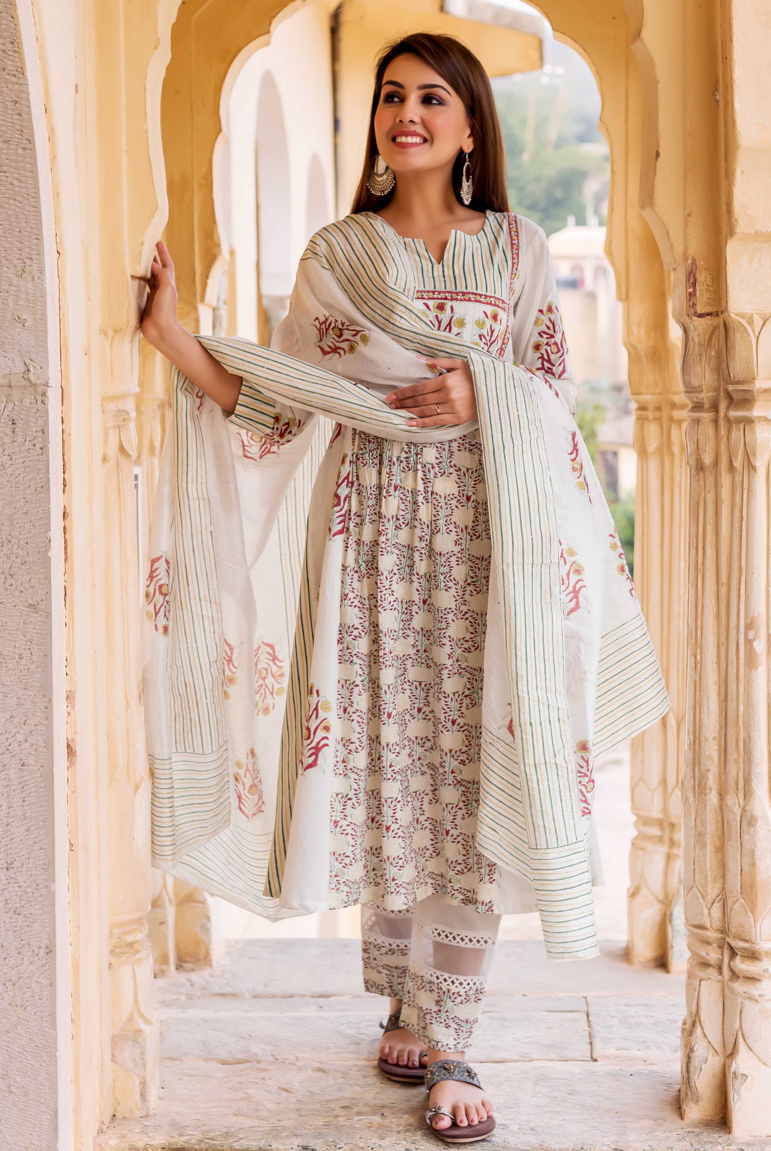 Woman wearing white hand-block-printed kurta with red and yellow floral patterns and green stripes.