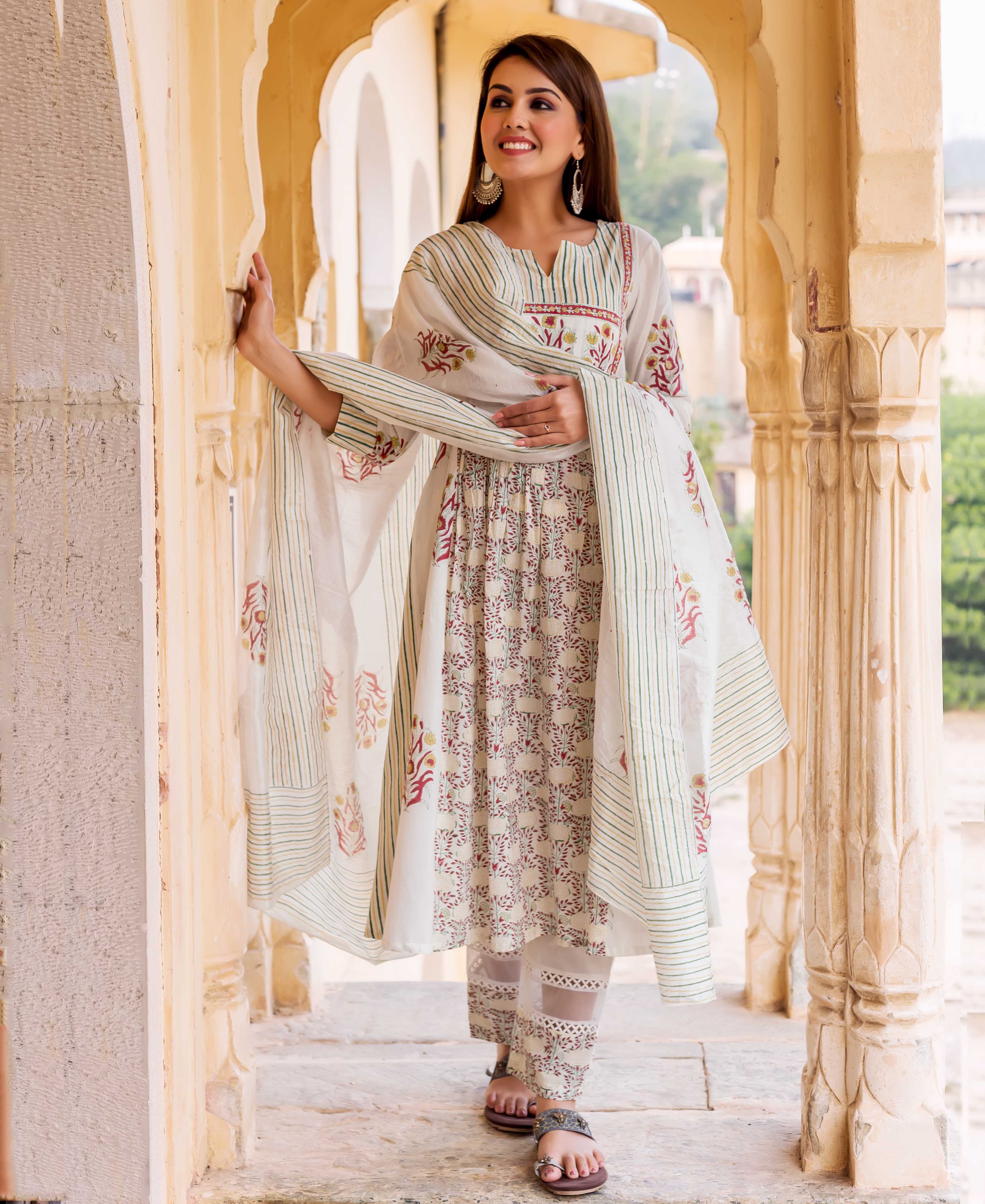 Woman wearing white hand-block-printed kurta with red and yellow floral patterns and green stripes.