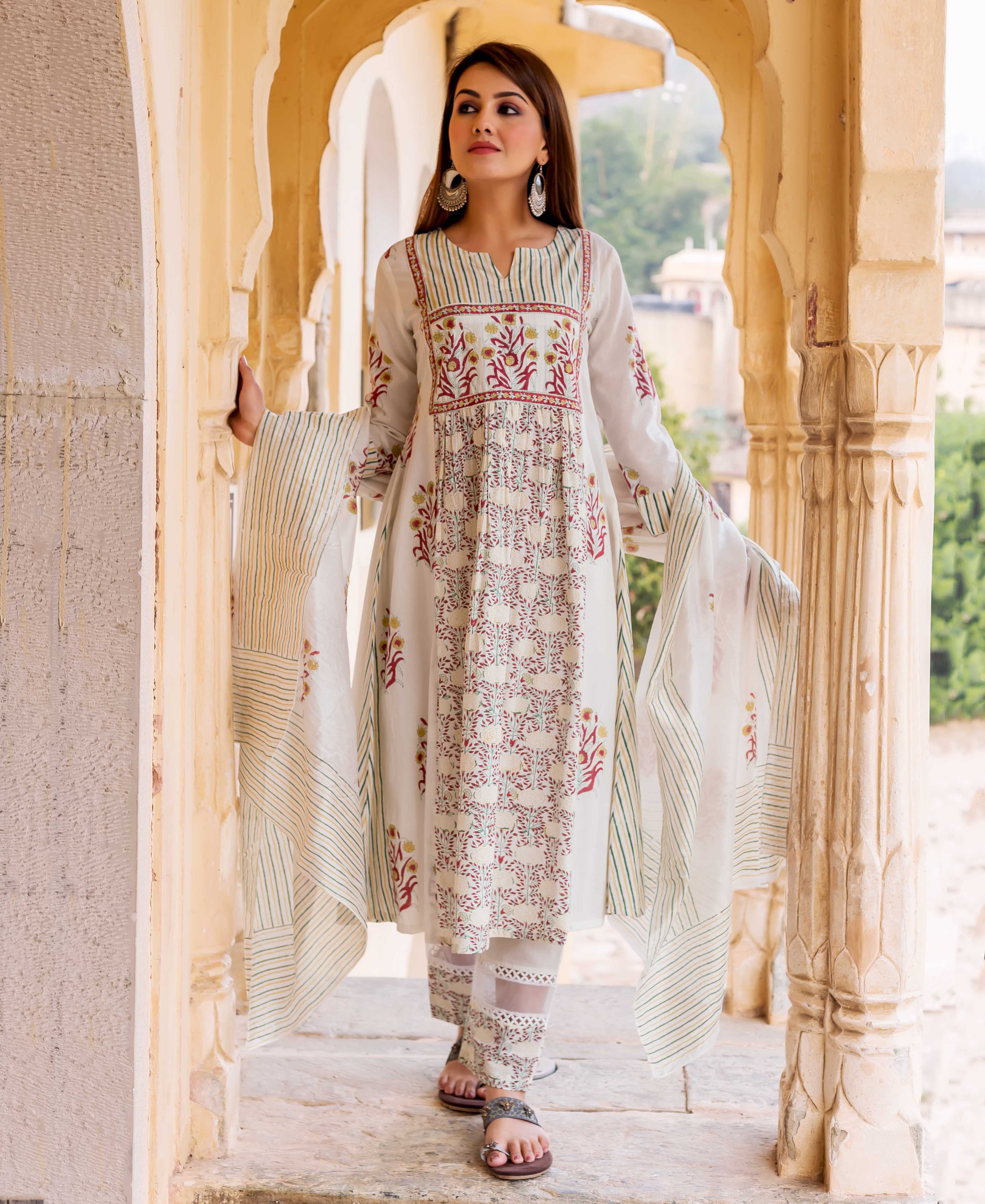 Model wearing a white hand-block printed kurta set with vibrant floral and striped patterns.