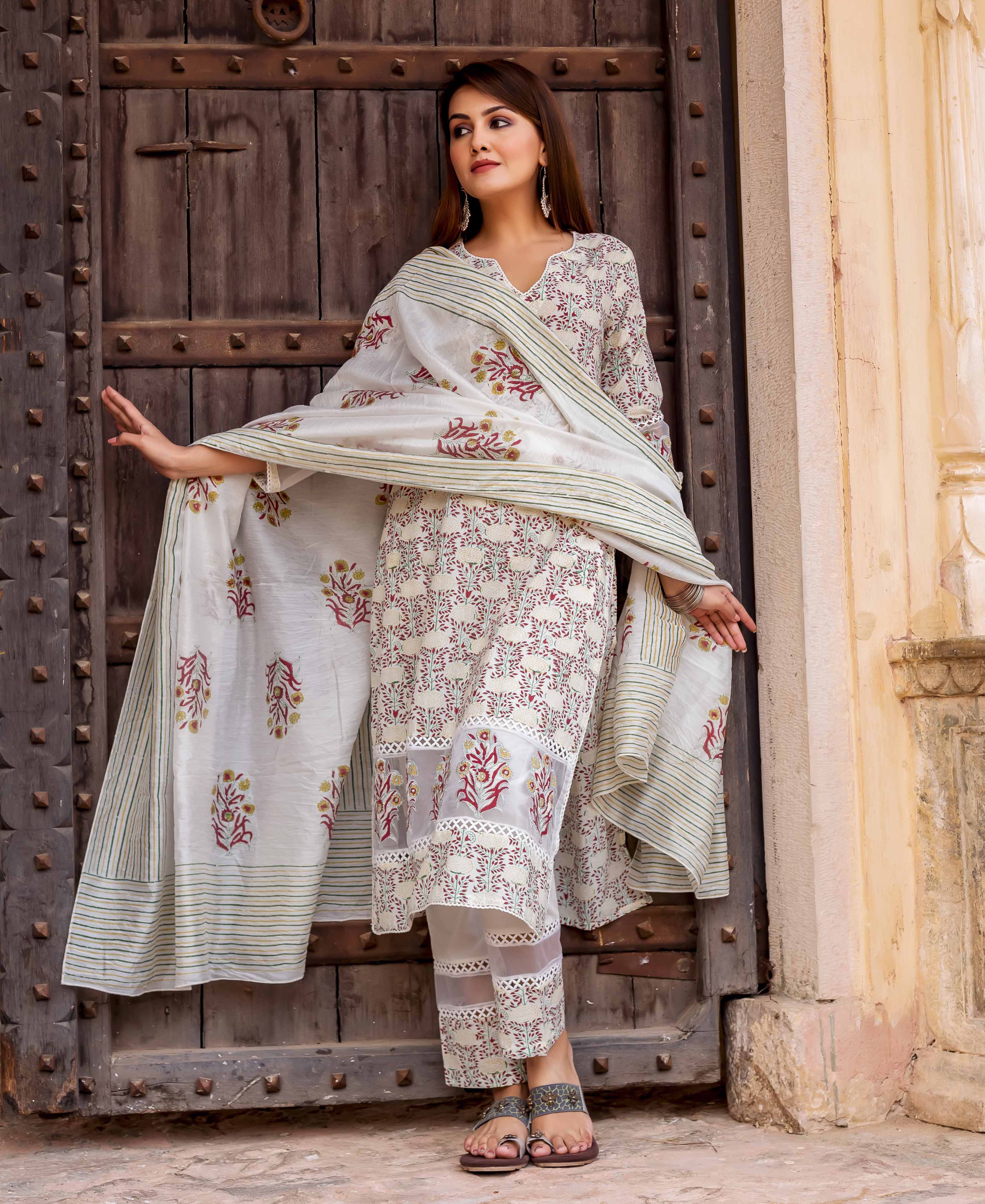 Model in off-white hand-block-printed suit with red floral print and sheer-paneled pants.