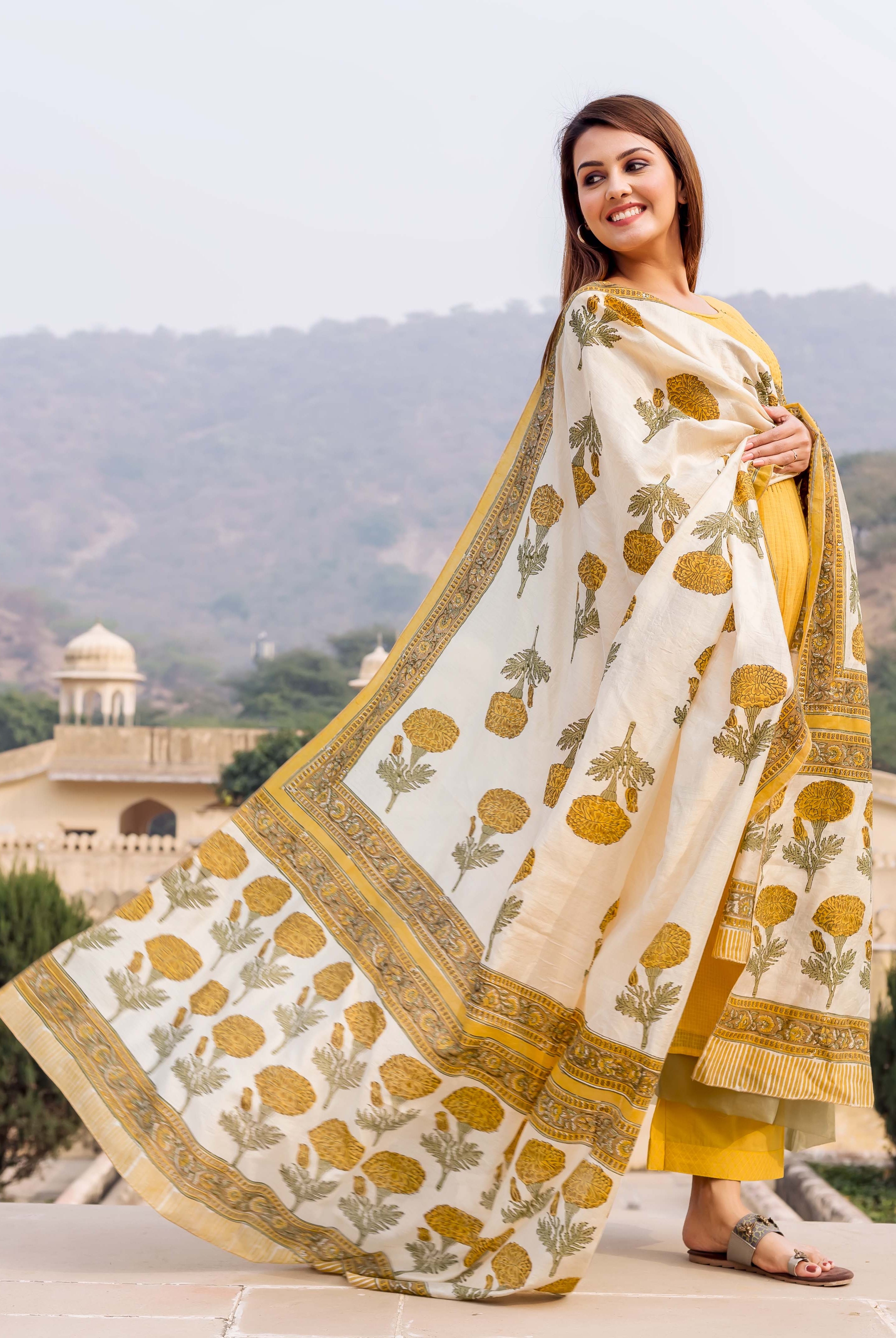 Side view model wearing honey yellow kurta set with floral block print dupatta.