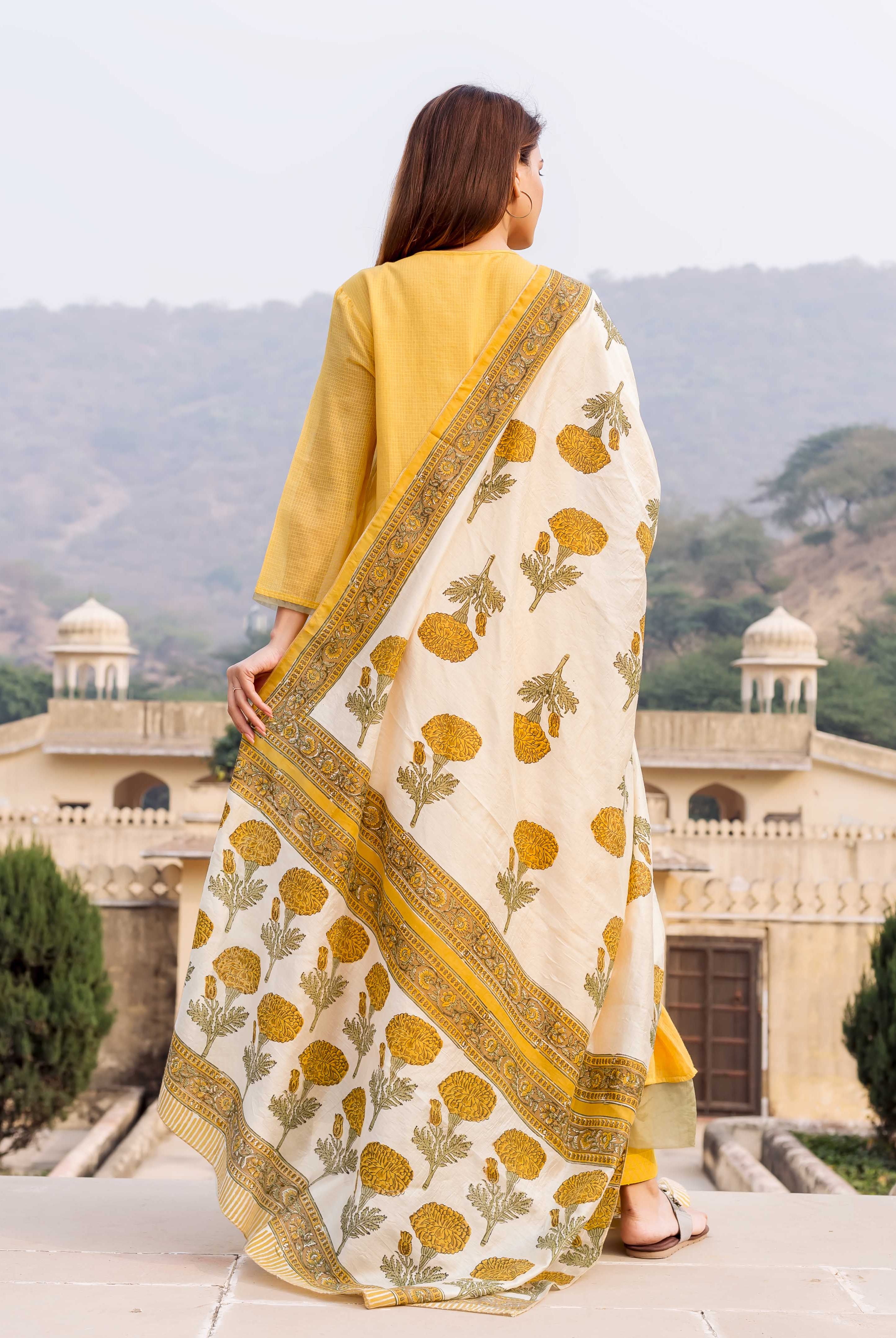 Rear view of model in honey yellow kurta and white hand-block printed floral dupatta.