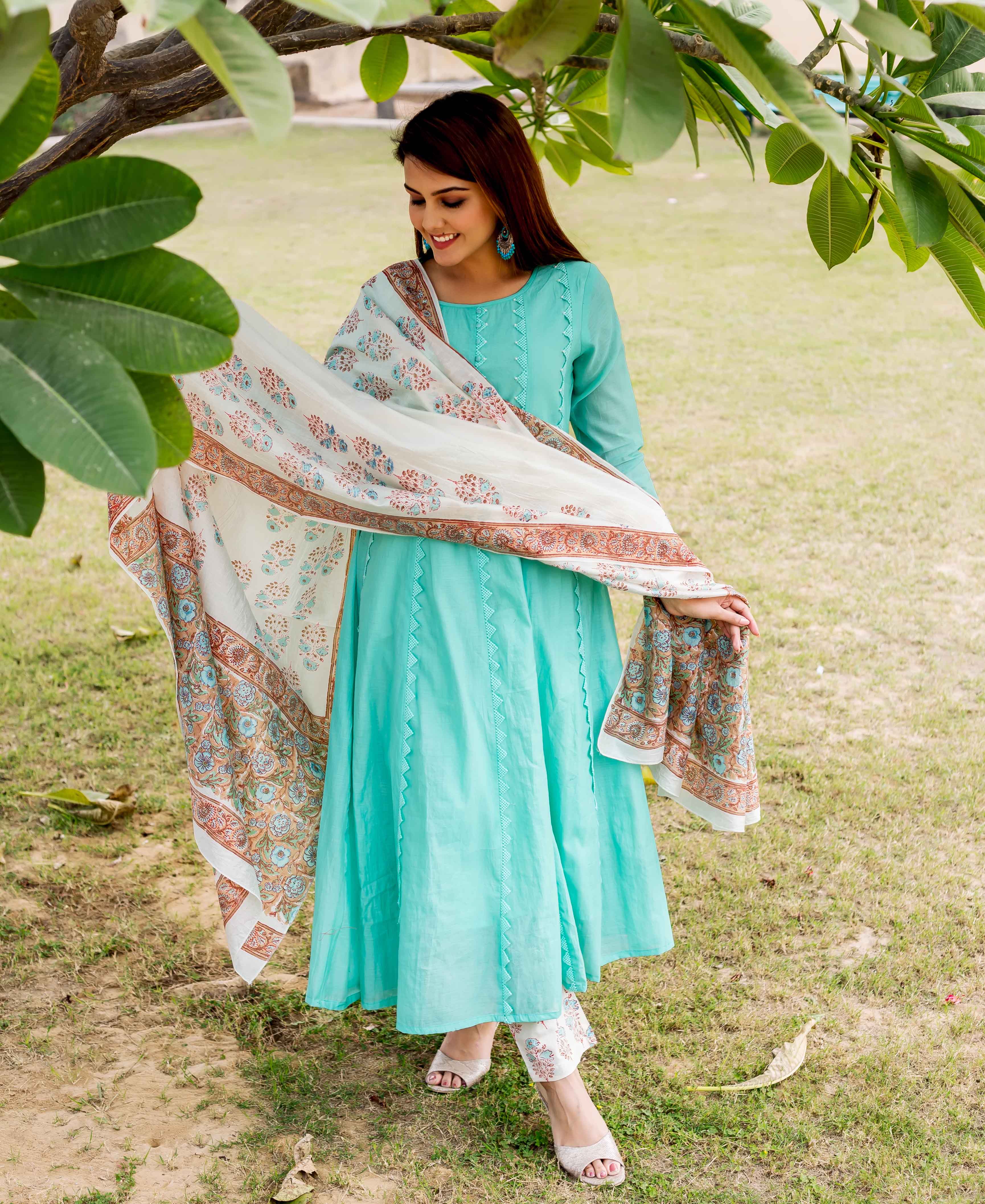 Smiling model in a sea green kurta with a flowing white block-printed dupatta and matching bottoms.
