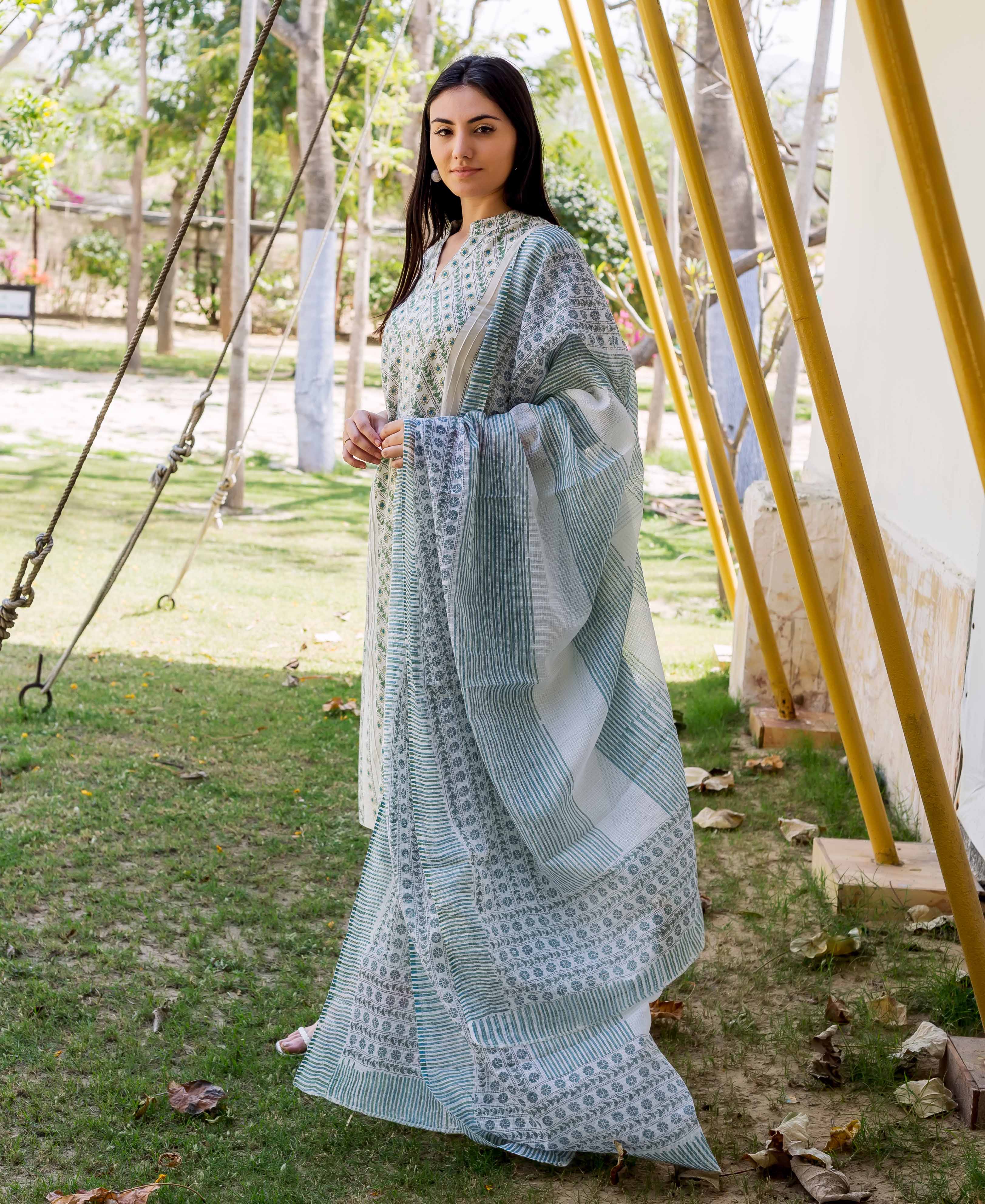 A woman in a long, white and green hand-block-printed kurta with a matching dupatta.