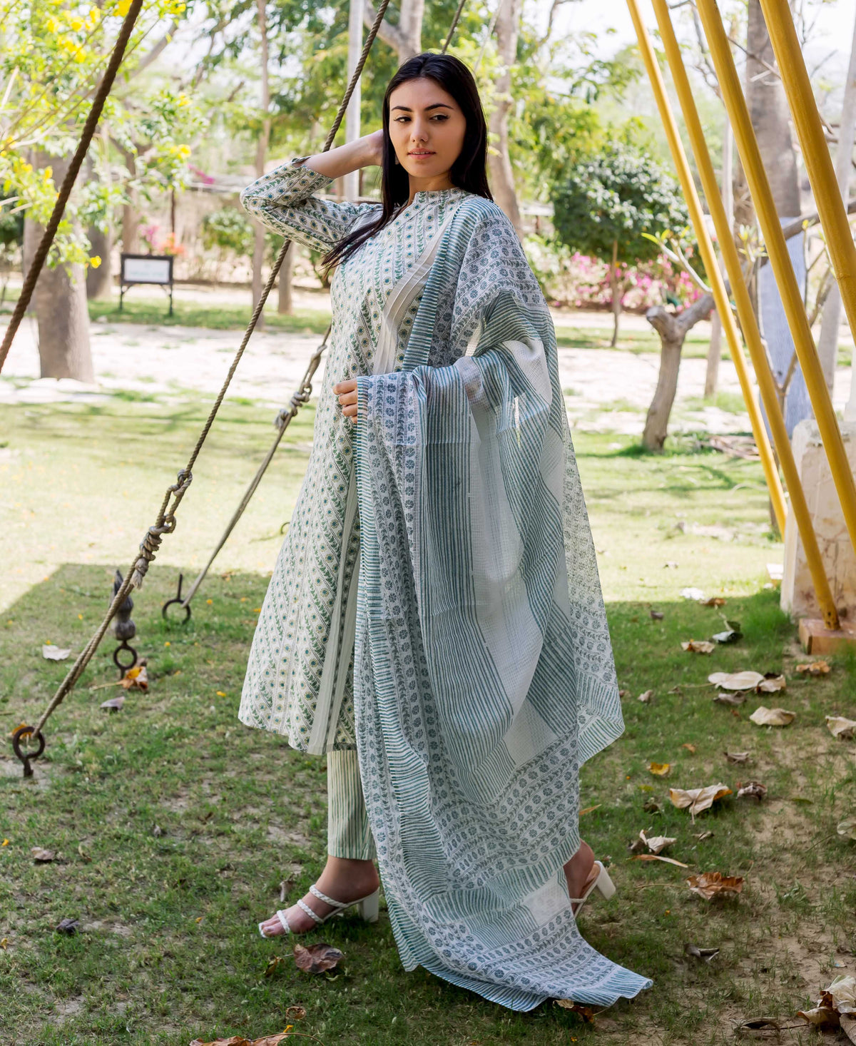 A woman in a white and green hand-block-printed kurta with a matching dupatta.