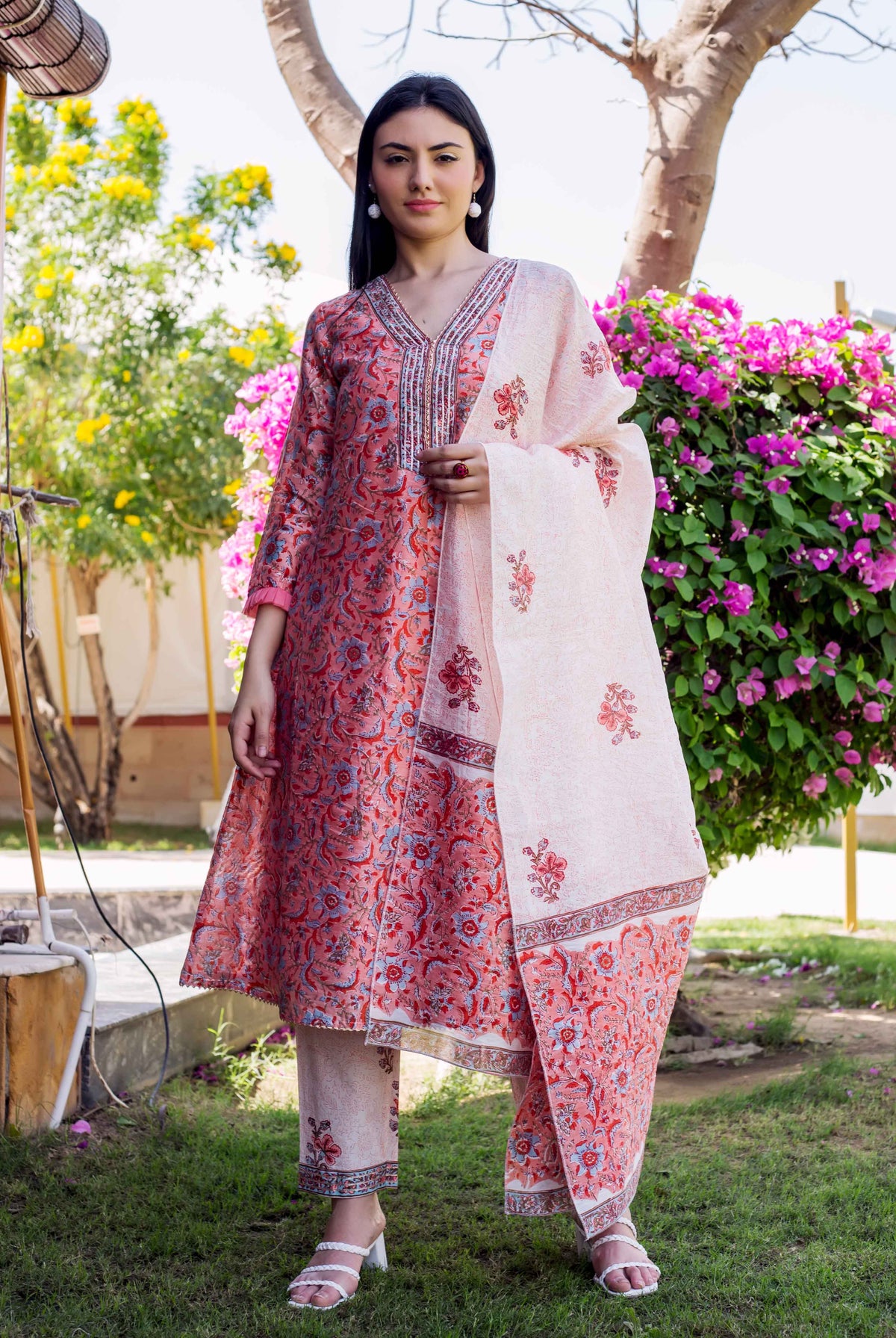 Model wearing a peach and red block-printed A-line kurta set with floral patterns.