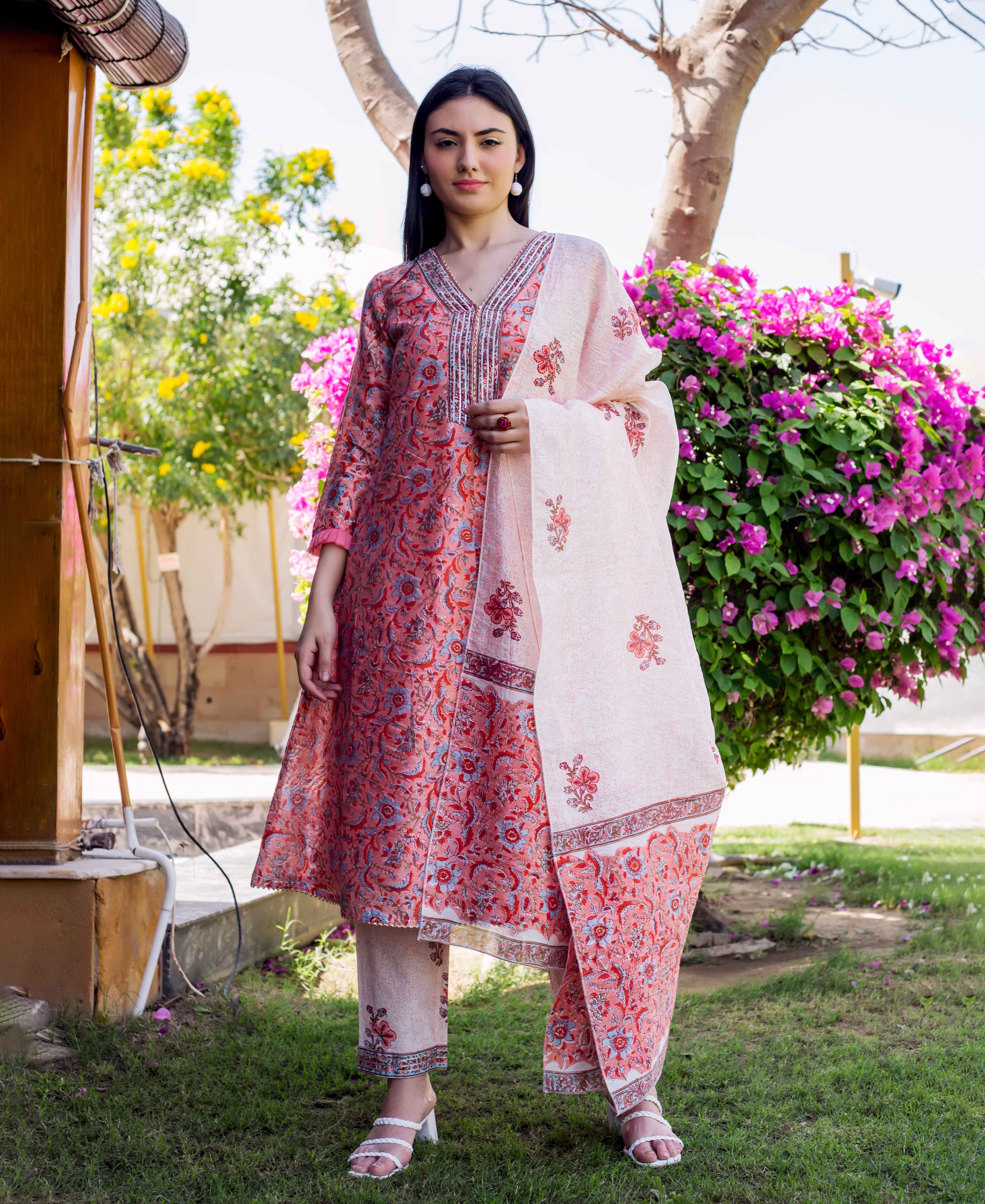 Model wearing a peach and red block-printed A-line kurta set with floral patterns.