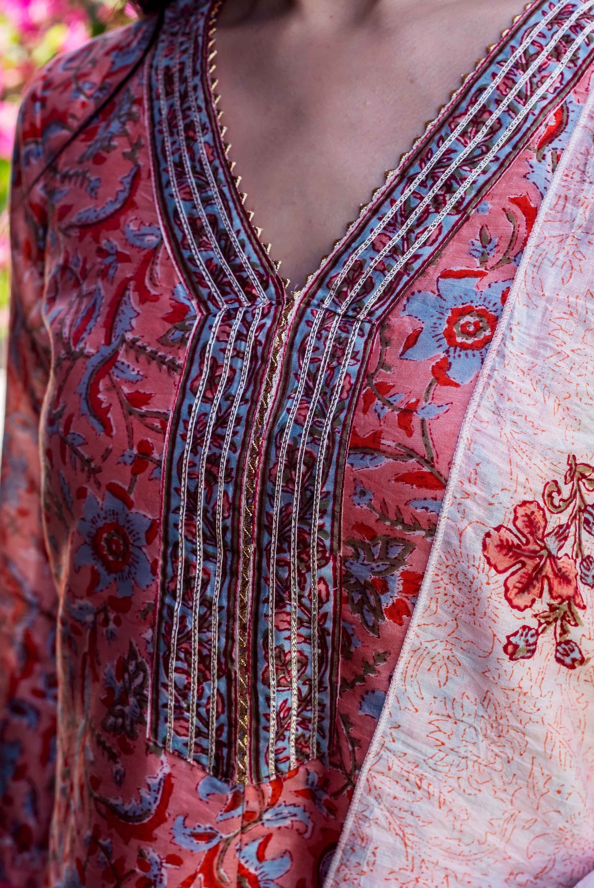 Close-up of pink Suhasini Block Printed Kurta with blue floral design and embellished V-neck.