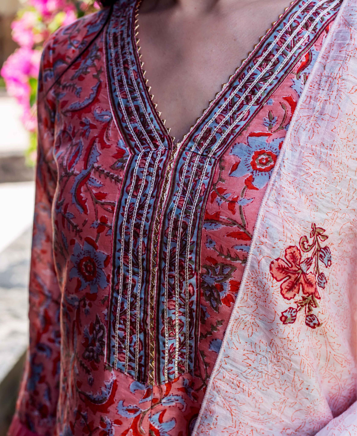 Close-up of pink Suhasini Block Printed Kurta with blue floral design and embellished V-neck.