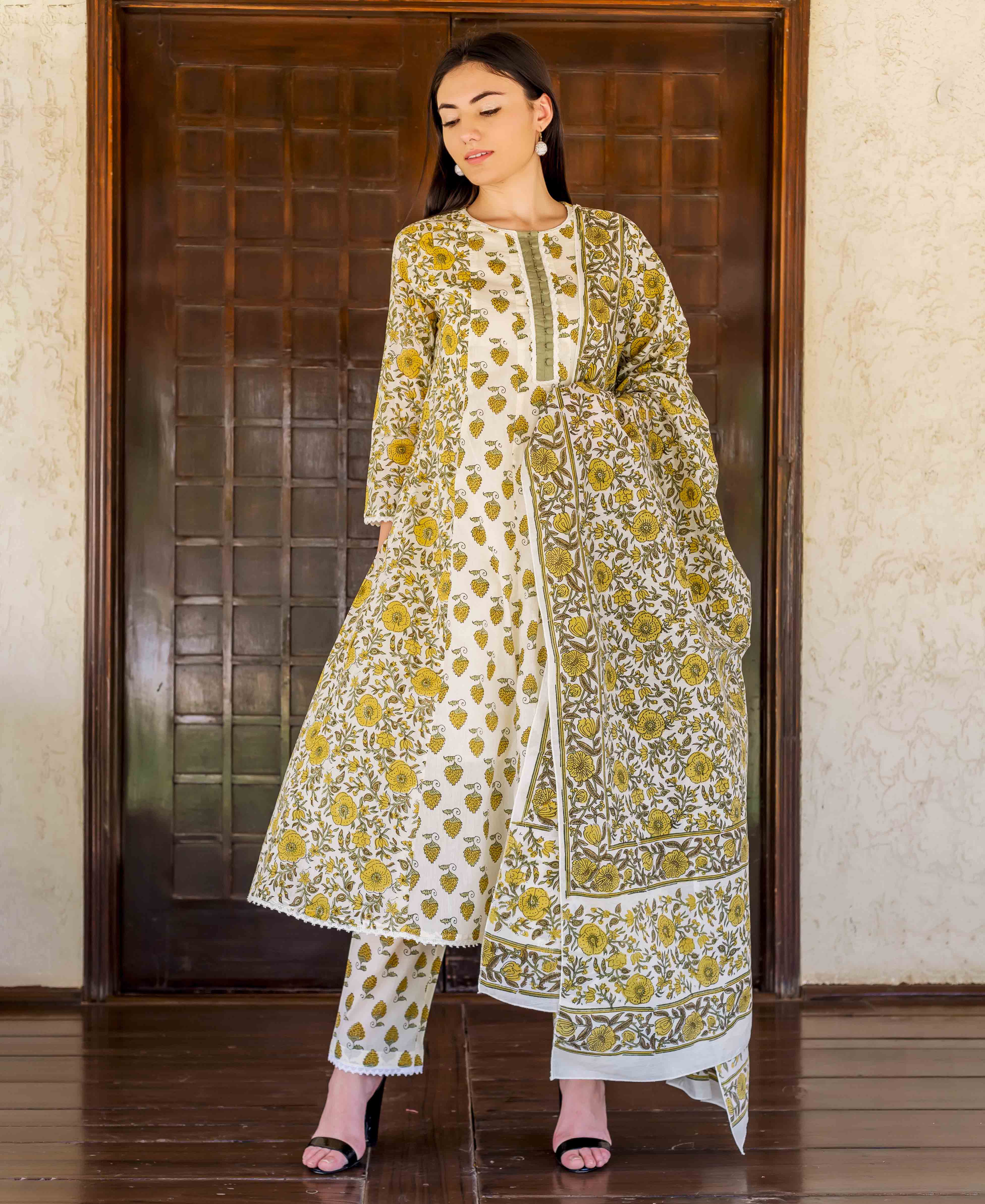 Front view of model in white and ochre block print A-line kurta set with dupatta.
