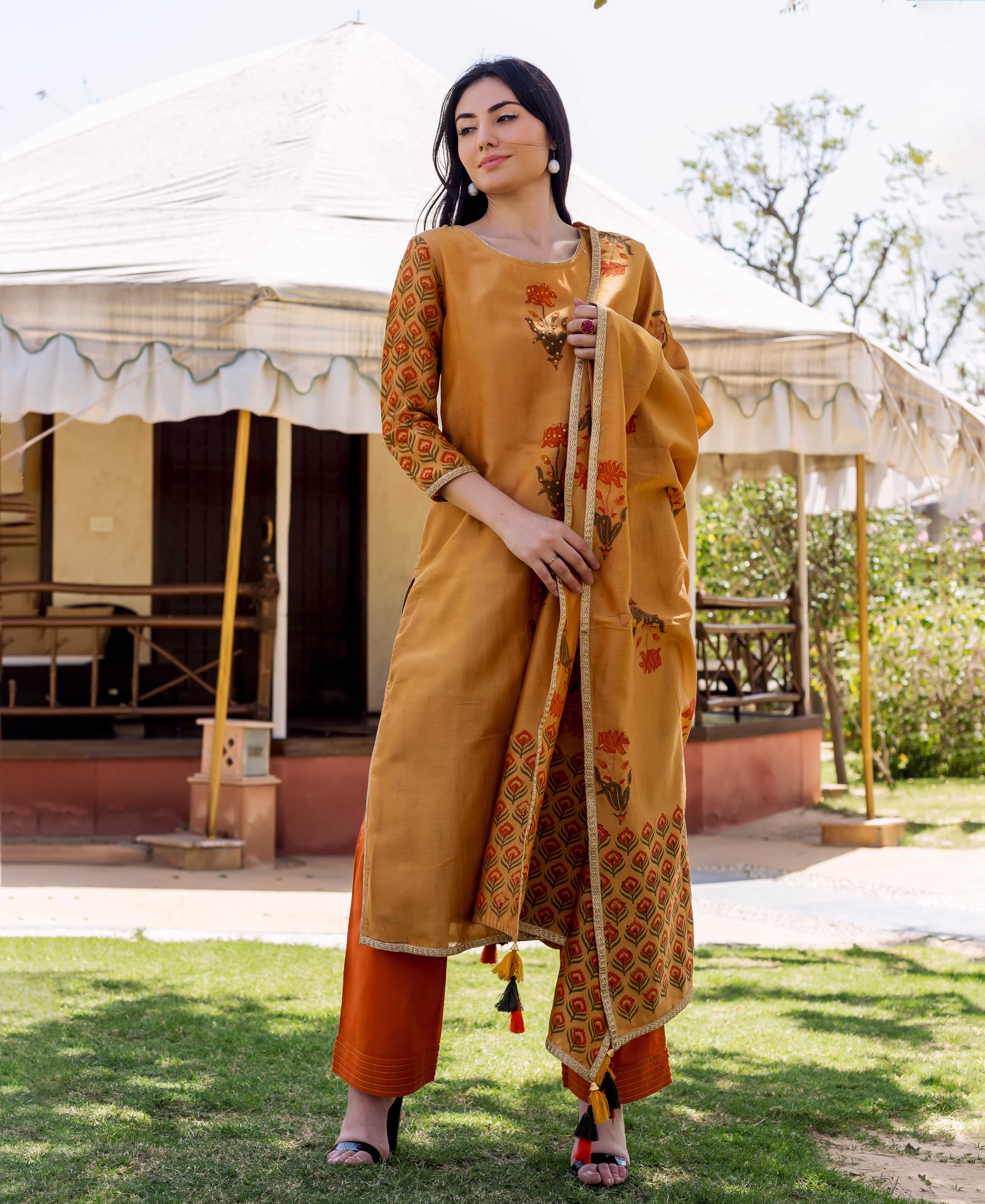 Model in mustard yellow block-printed and embroidered kurta set with orange pants and matching dupatta.