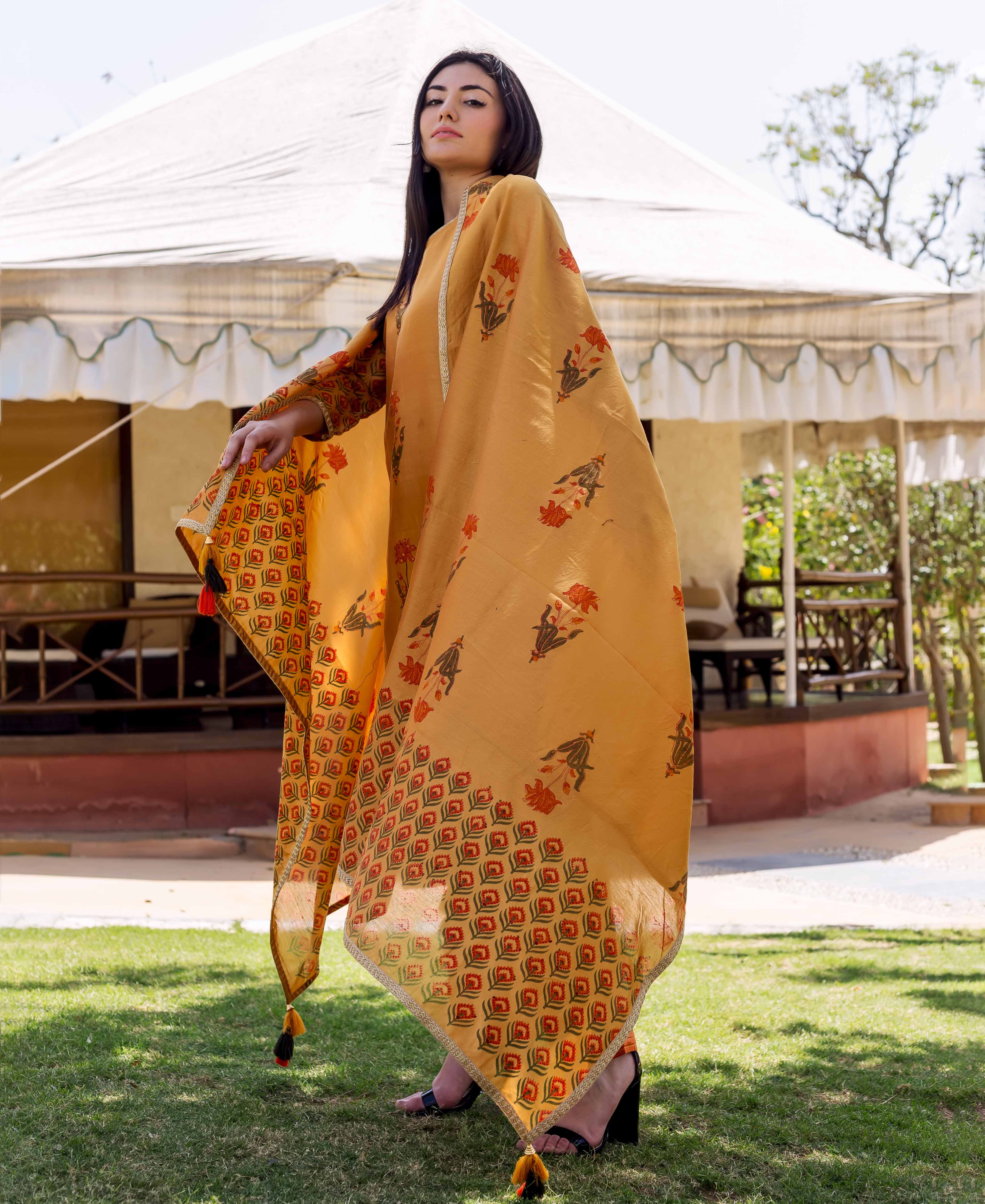Full-body shot of woman modeling an ochre hand-block printed kurta set with floral and geometric patterns.