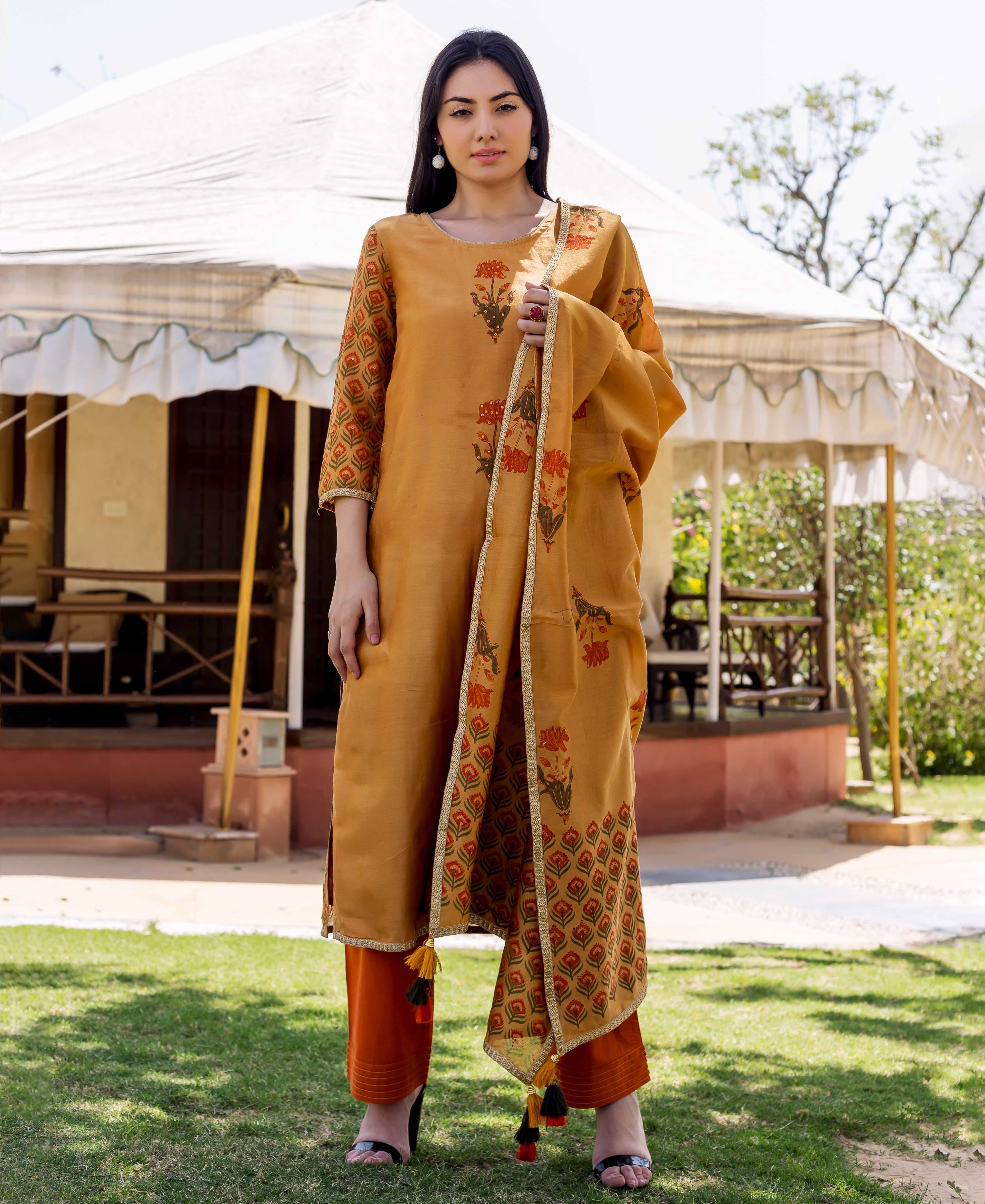Full-length model in golden block-printed kurta with floral, geometric patterns, and orange pants.