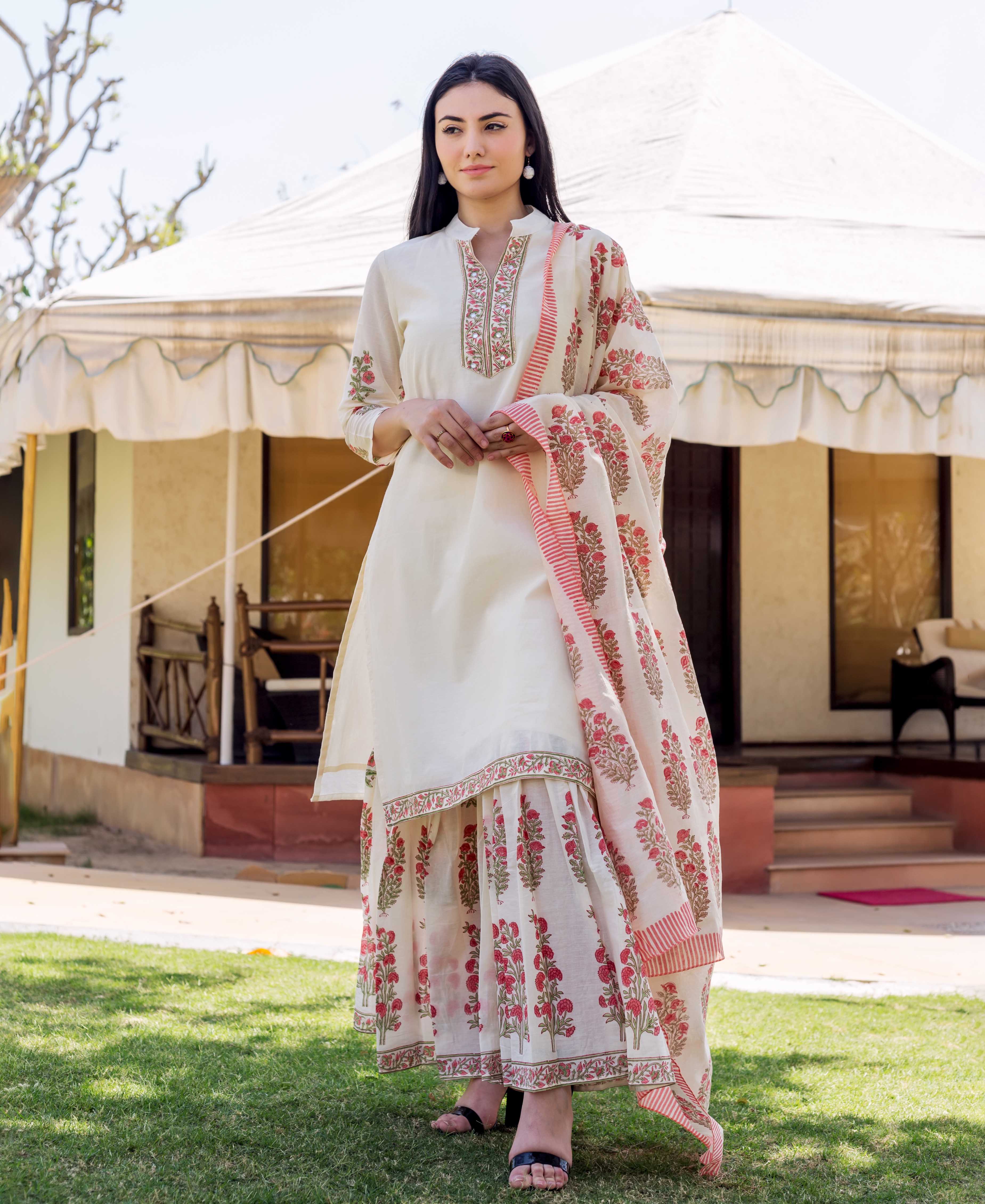 A woman in a long, white kurta with red and green floral patterns.