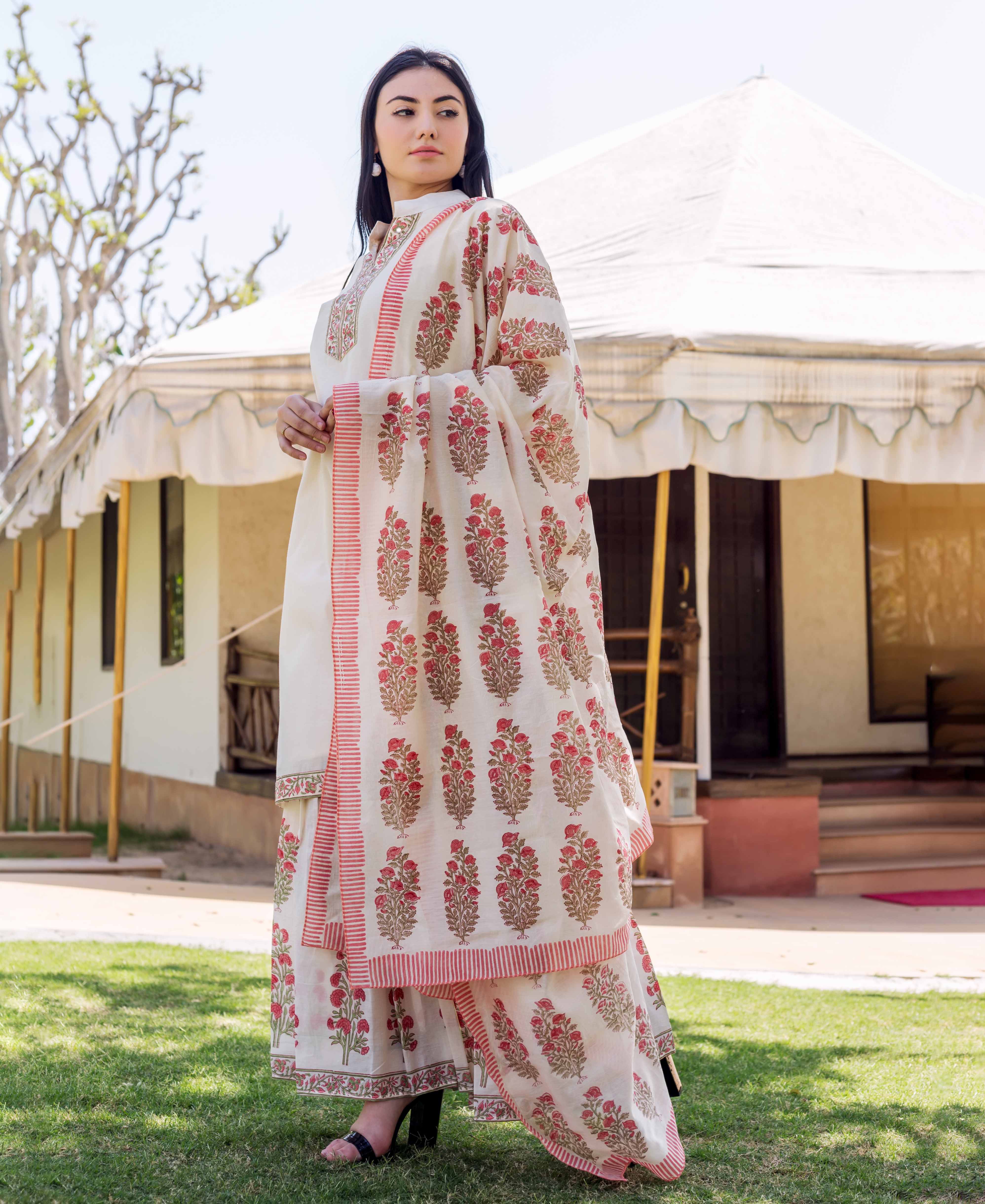 A woman in a long, white kurta with red and gold floral patterns.