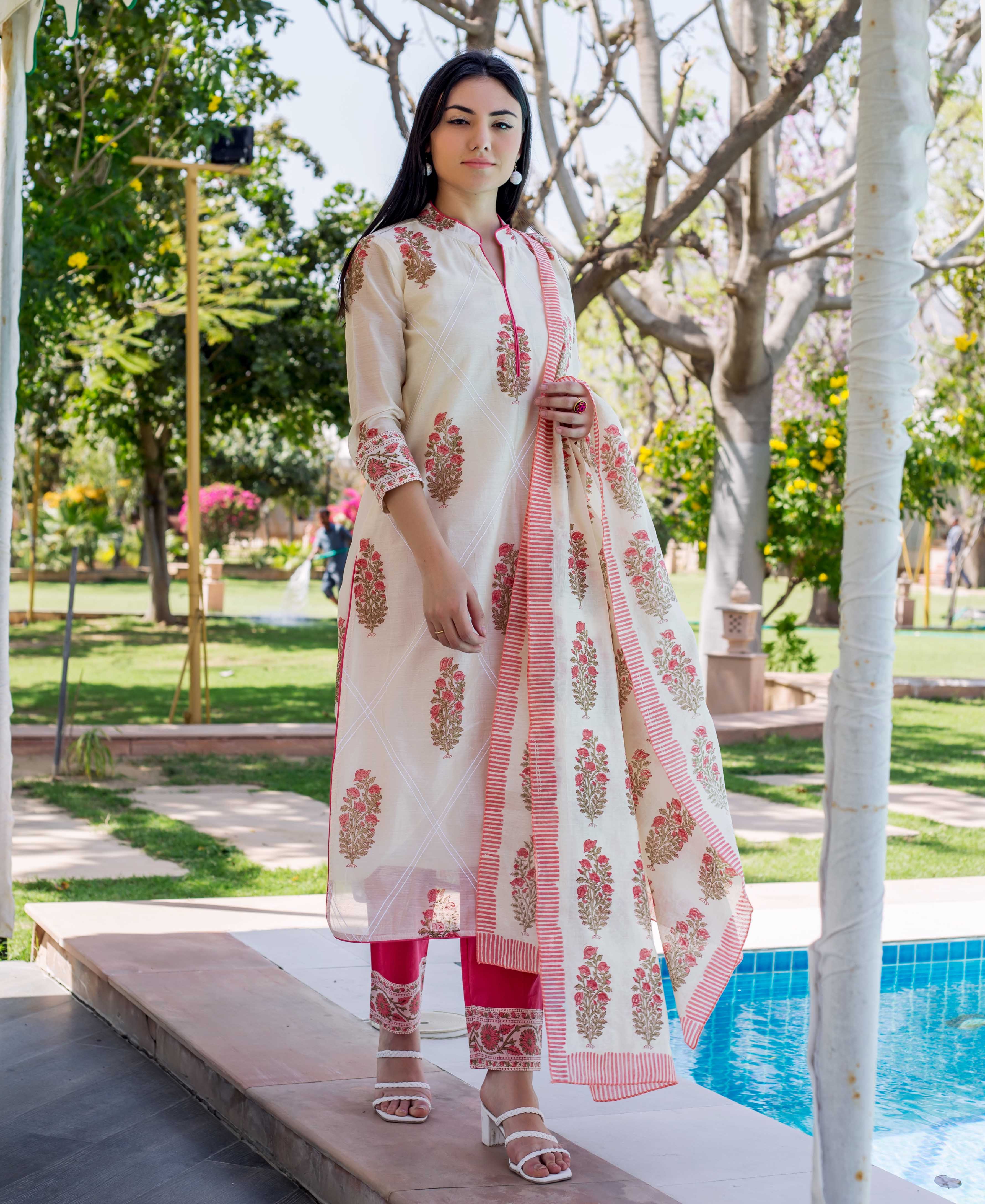 Woman in cream straight kurta, pink floral block print, matching dupatta, and fuchsia pants.
