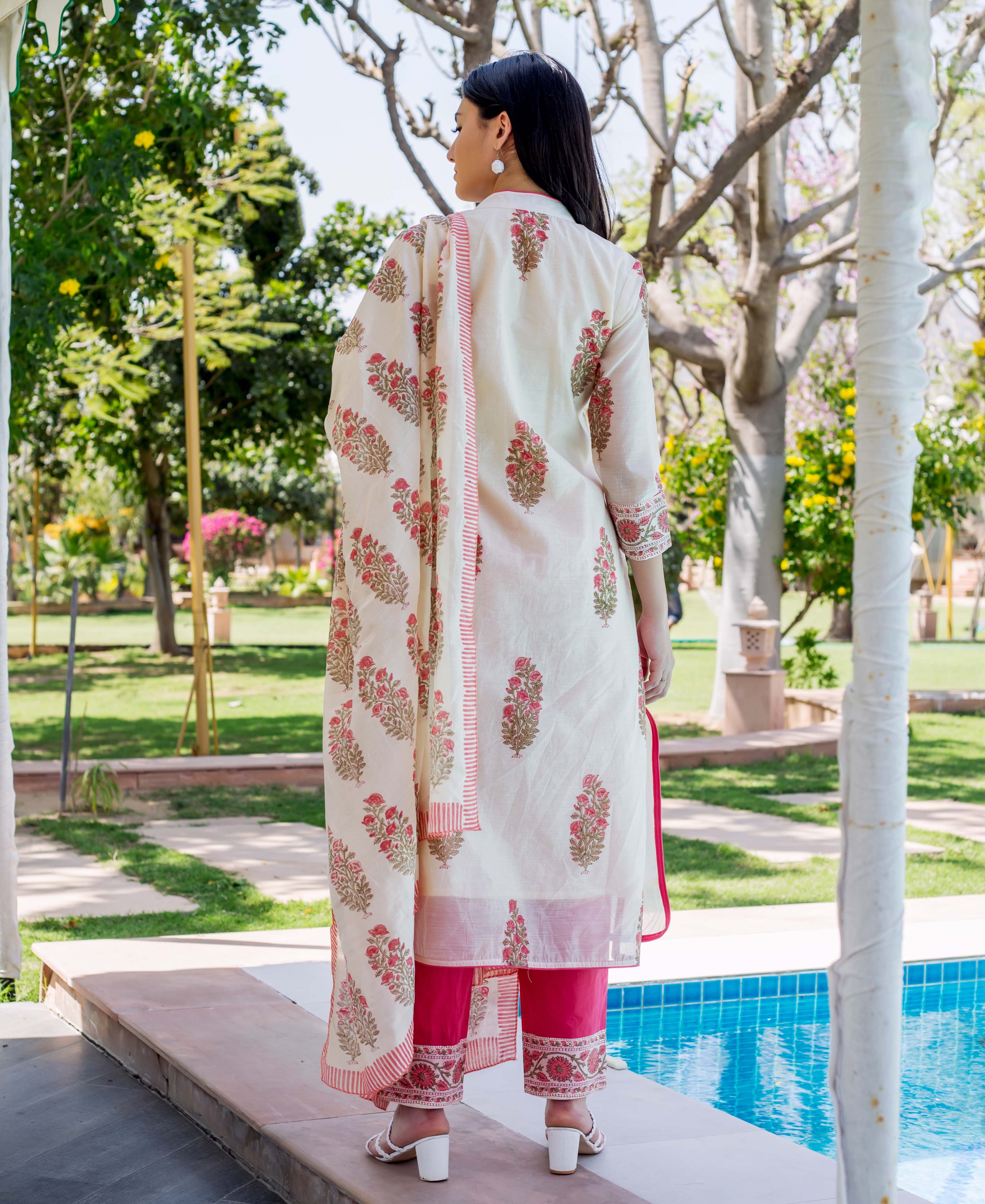Back view: woman in cream floral block print kurta set with bright pink pants.