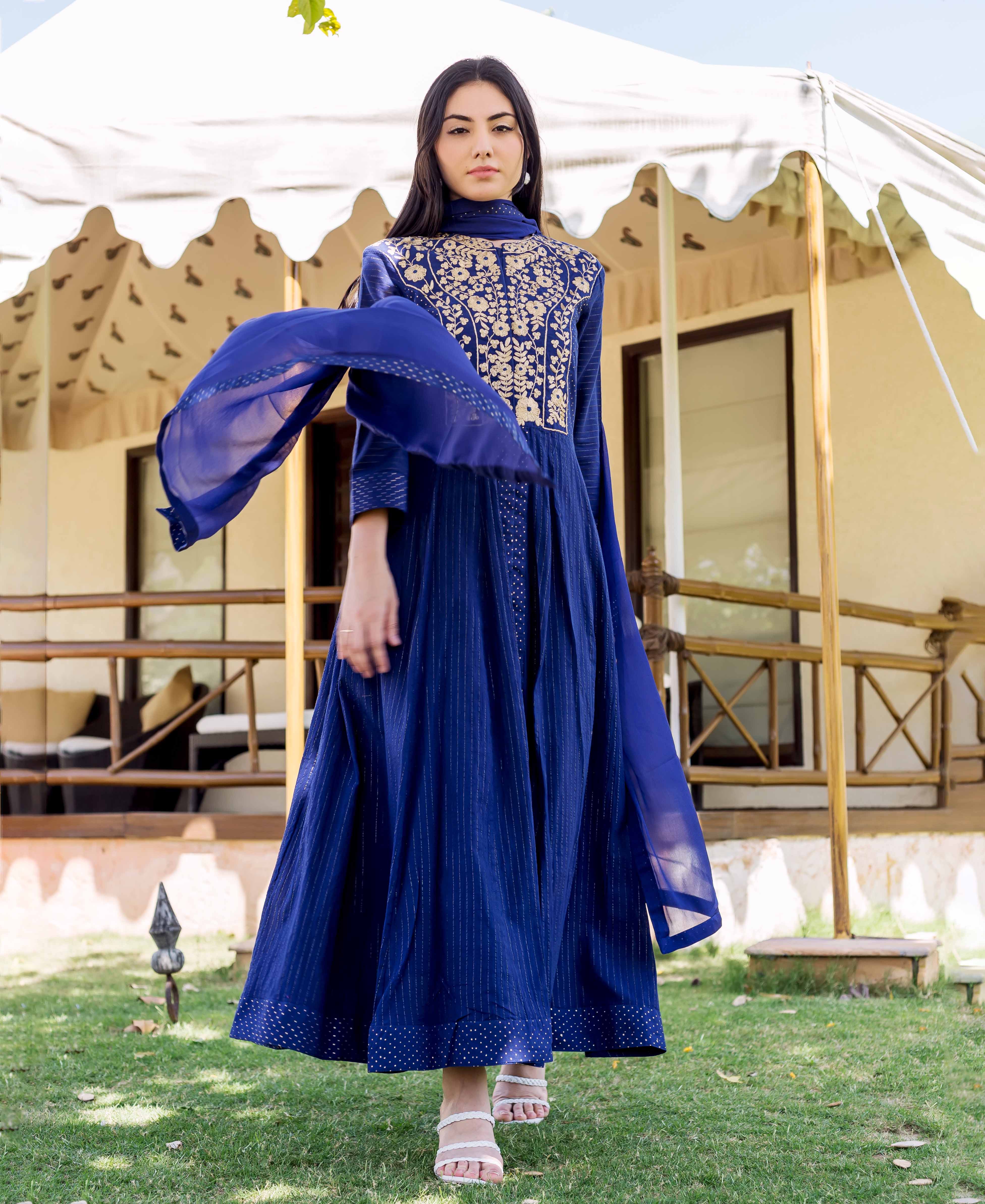 Model wears royal blue anarkali dress, gold embroidered yoke, subtle vertical print, and flowing dupatta.