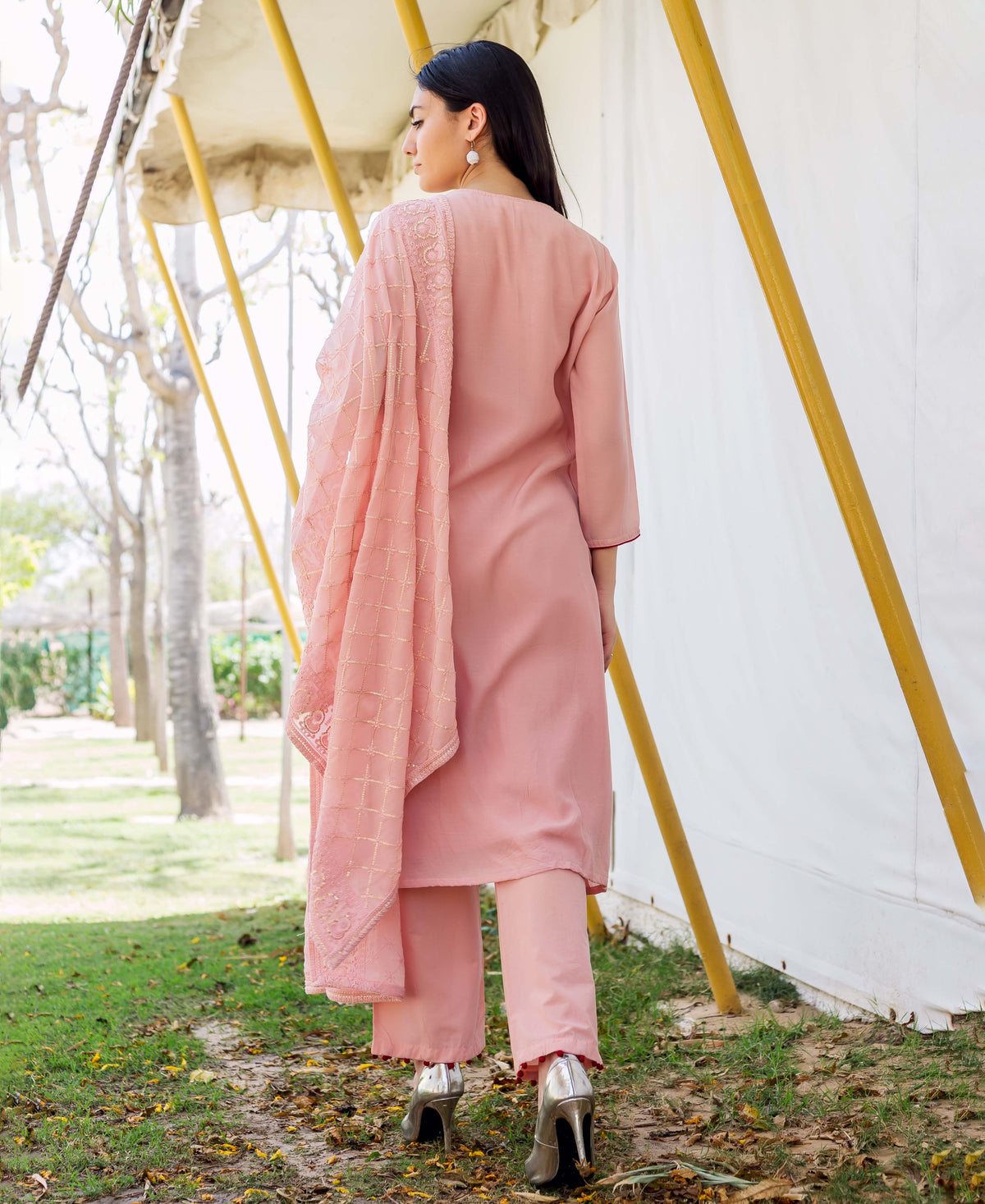 A woman in a dusty pink embroidered kurta with a matching dupatta, standing outdoors.
