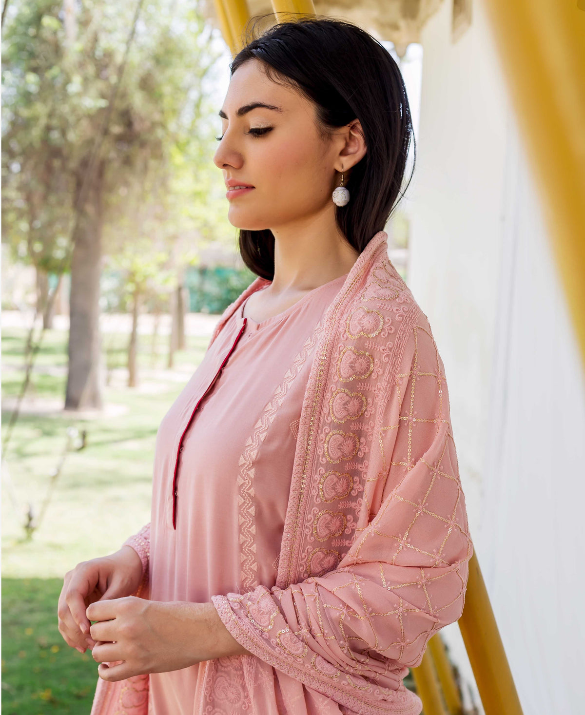 Side profile of a model wearing a dusty pink embroidered kurta with a matching shawl.