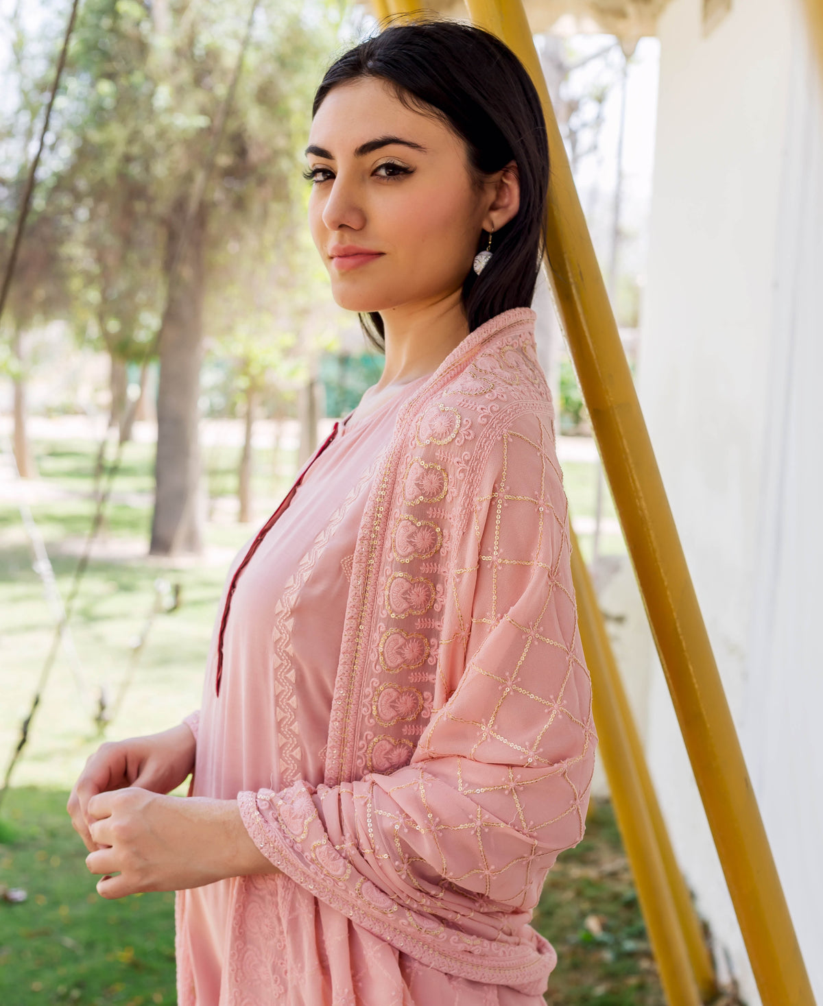 A woman wearing a dusty pink embroidered kurta with gold accents.