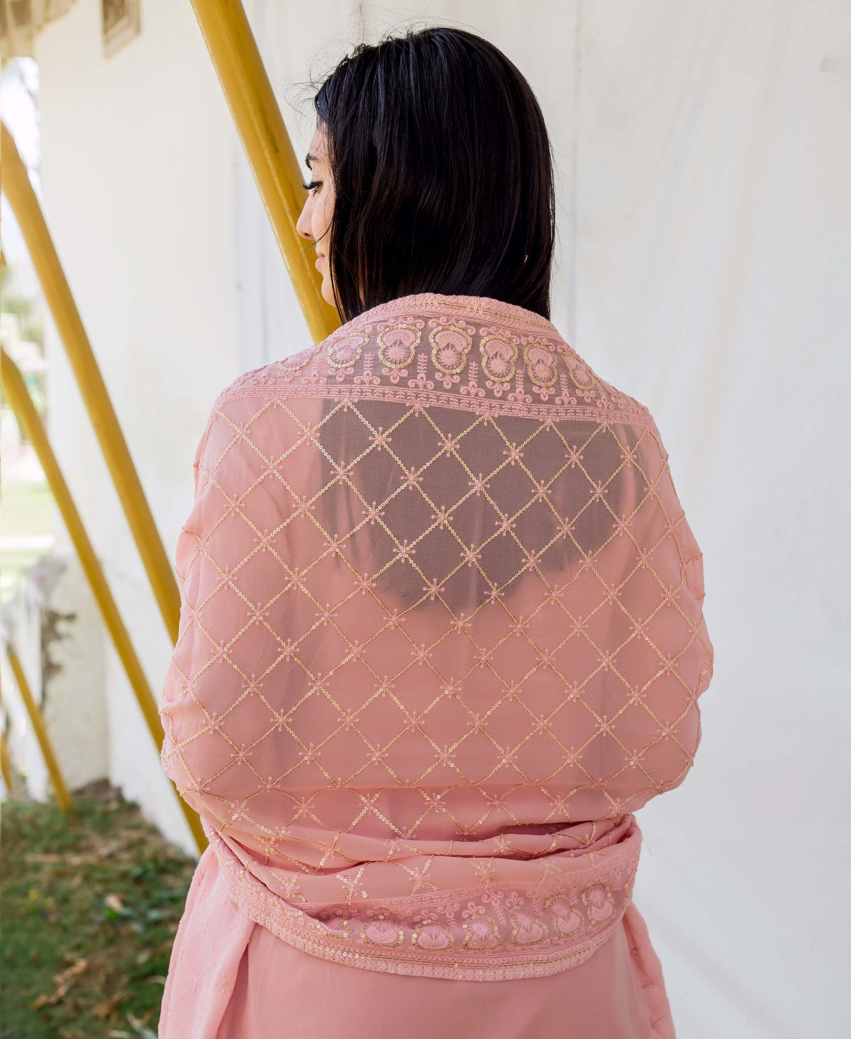 A woman wearing a dusty pink embroidered straight kurta with gold accents.