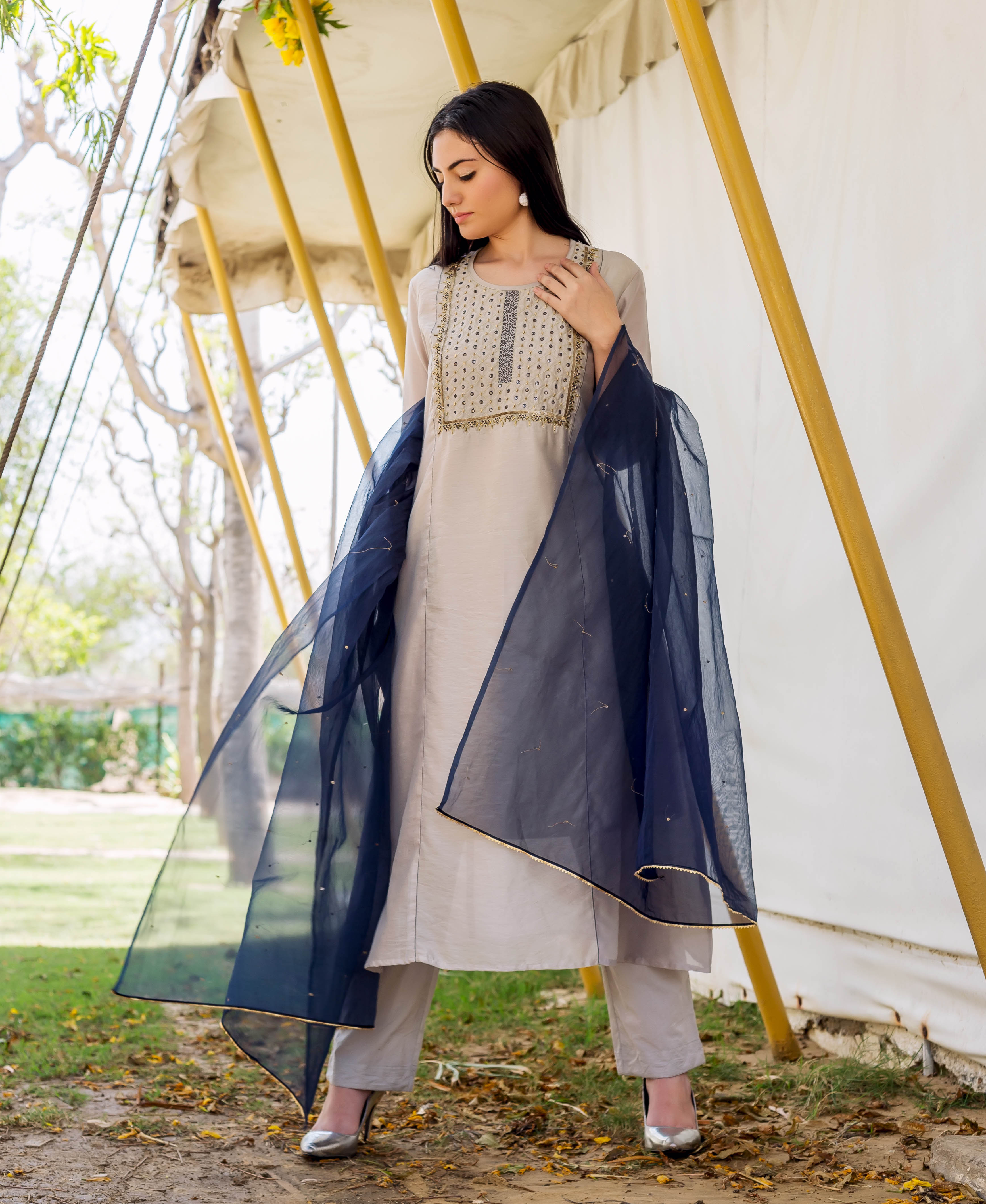Front view of model wearing a light grey embroidered kurta set with navy blue sheer dupatta.