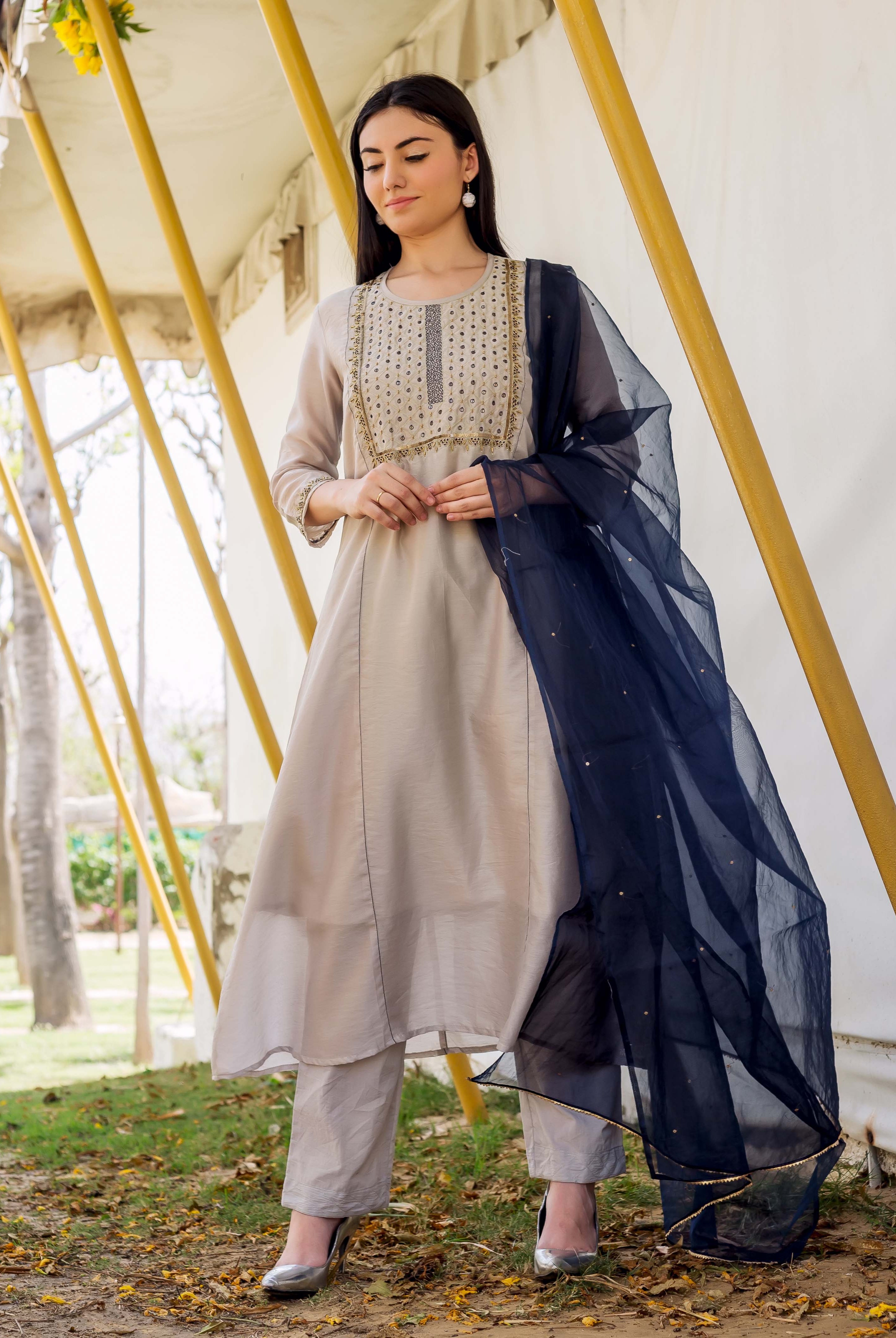 Model in a full shot wearing a grey embroidered kurta, matching pants, and navy dupatta.
