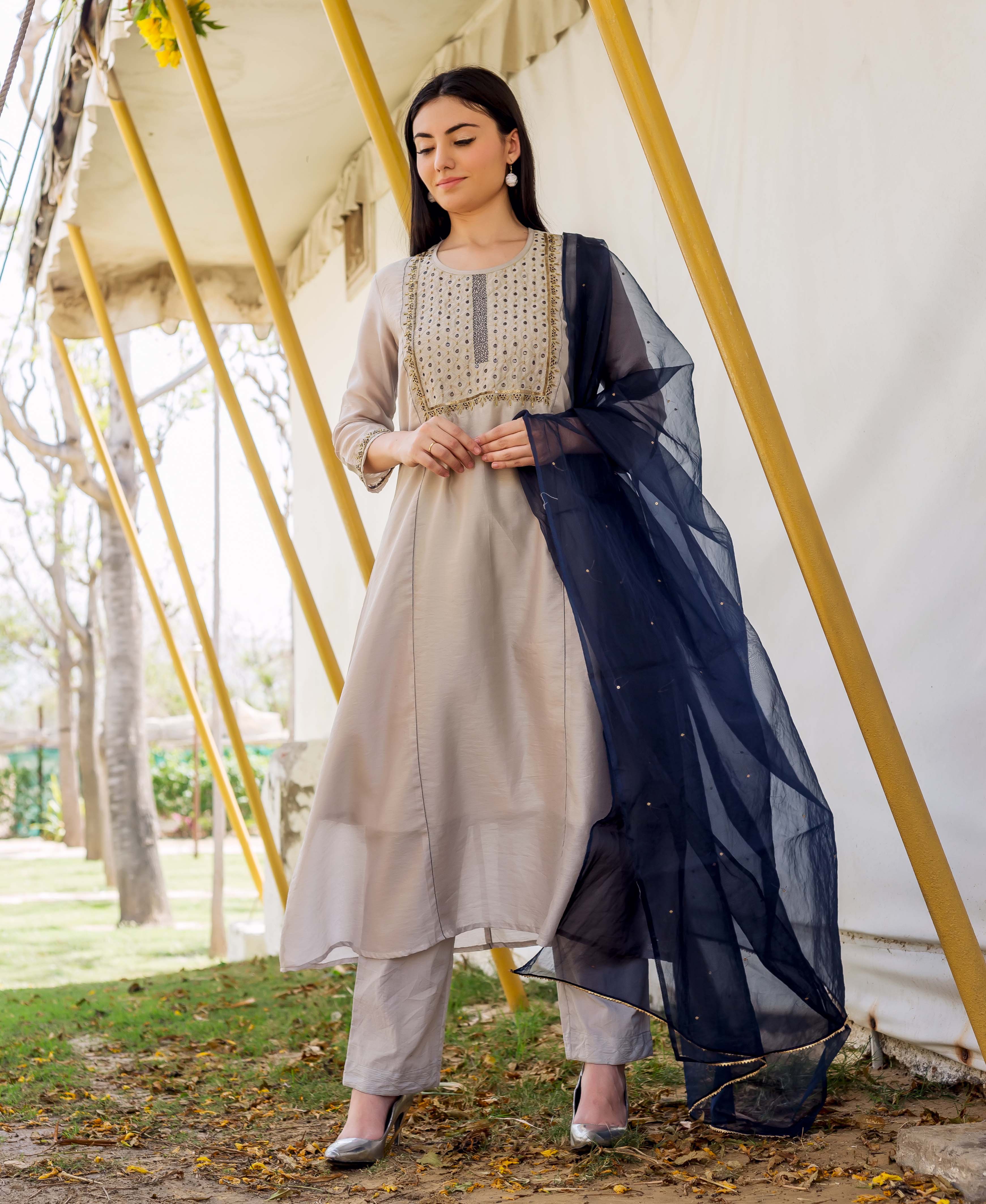 Model in a full shot wearing a grey embroidered kurta, matching pants, and navy dupatta.