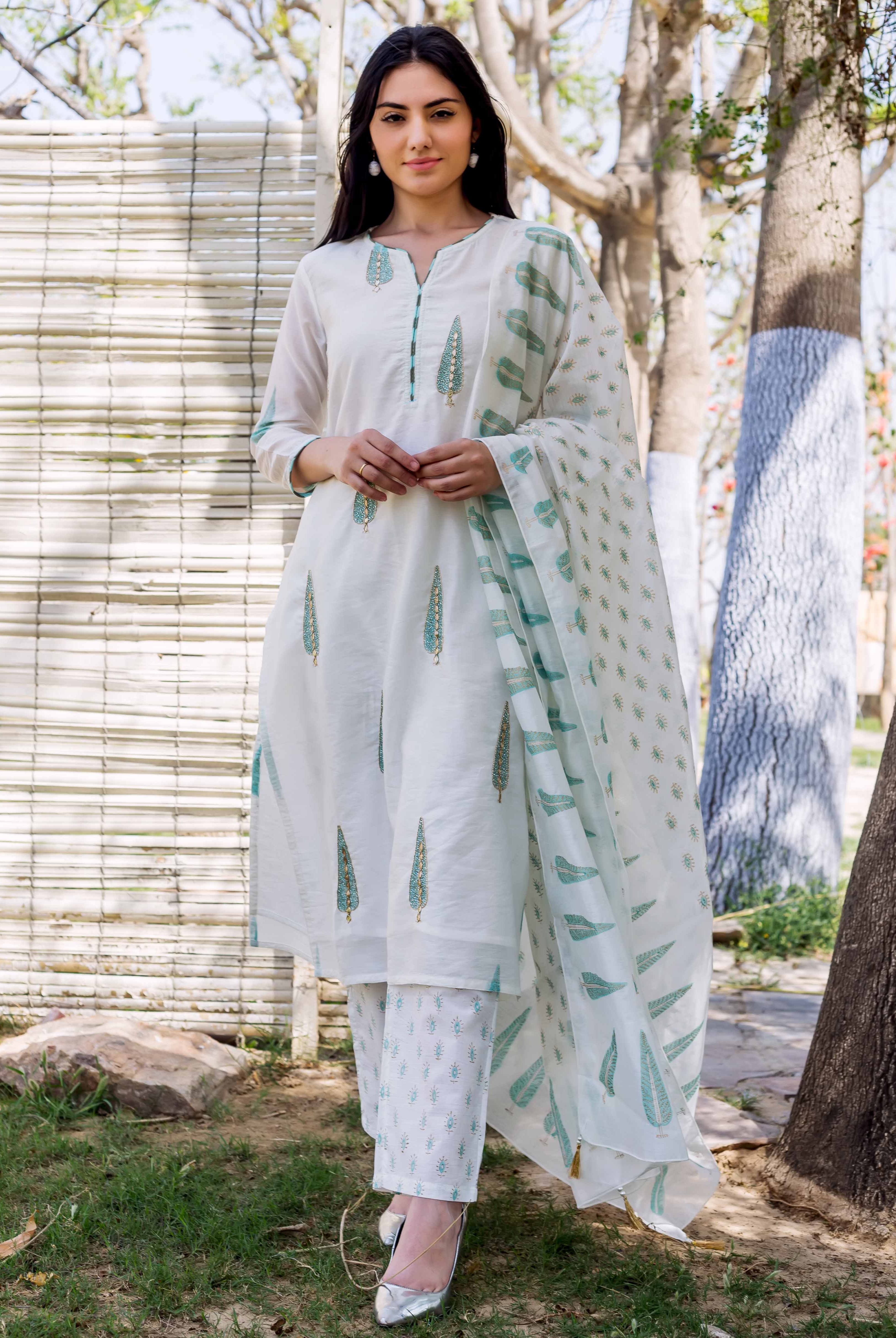 Model posing in a white hand block printed embroidered straight kurta set with green motifs.
