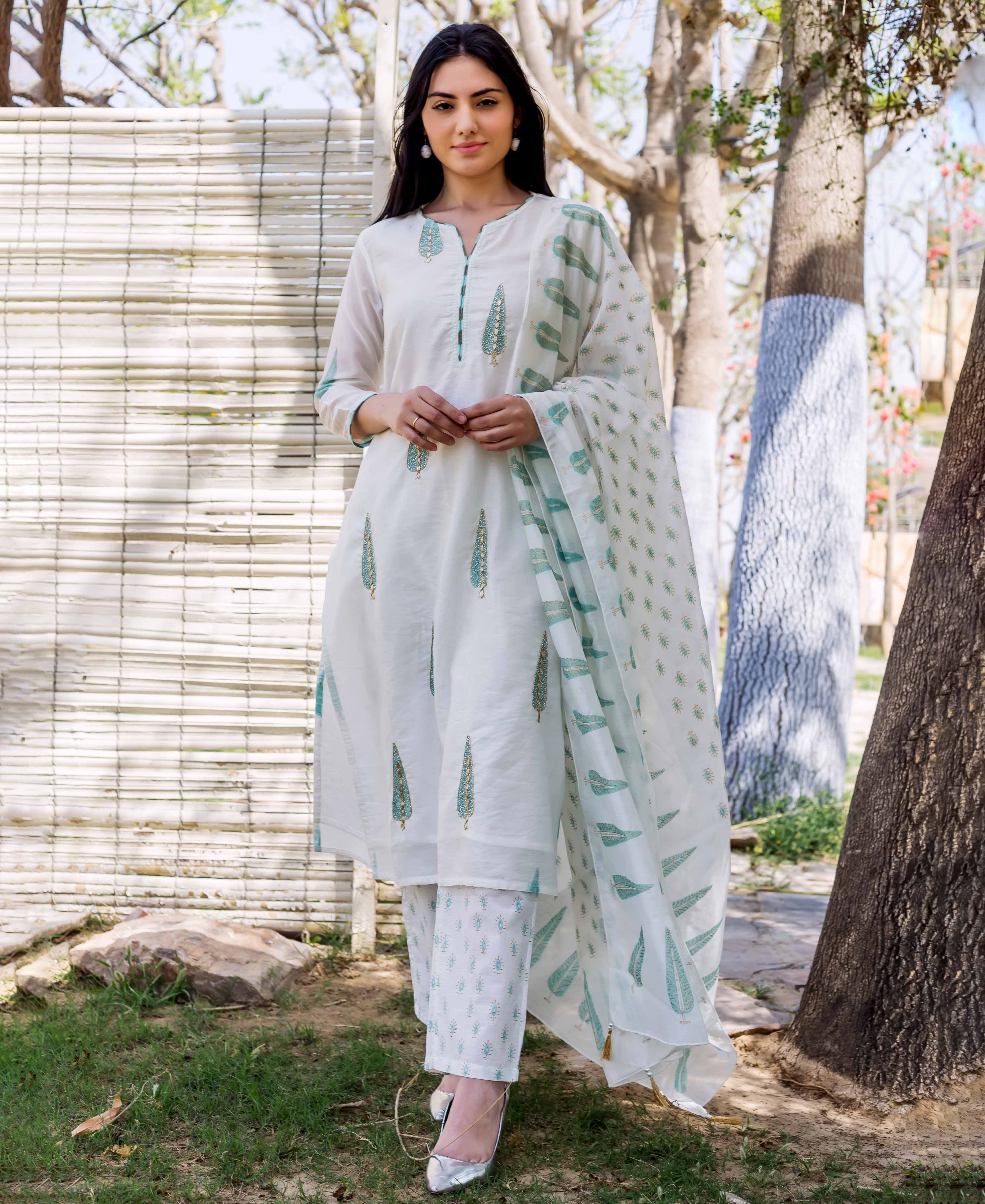 Model posing in a white hand block printed embroidered straight kurta set with green motifs.
