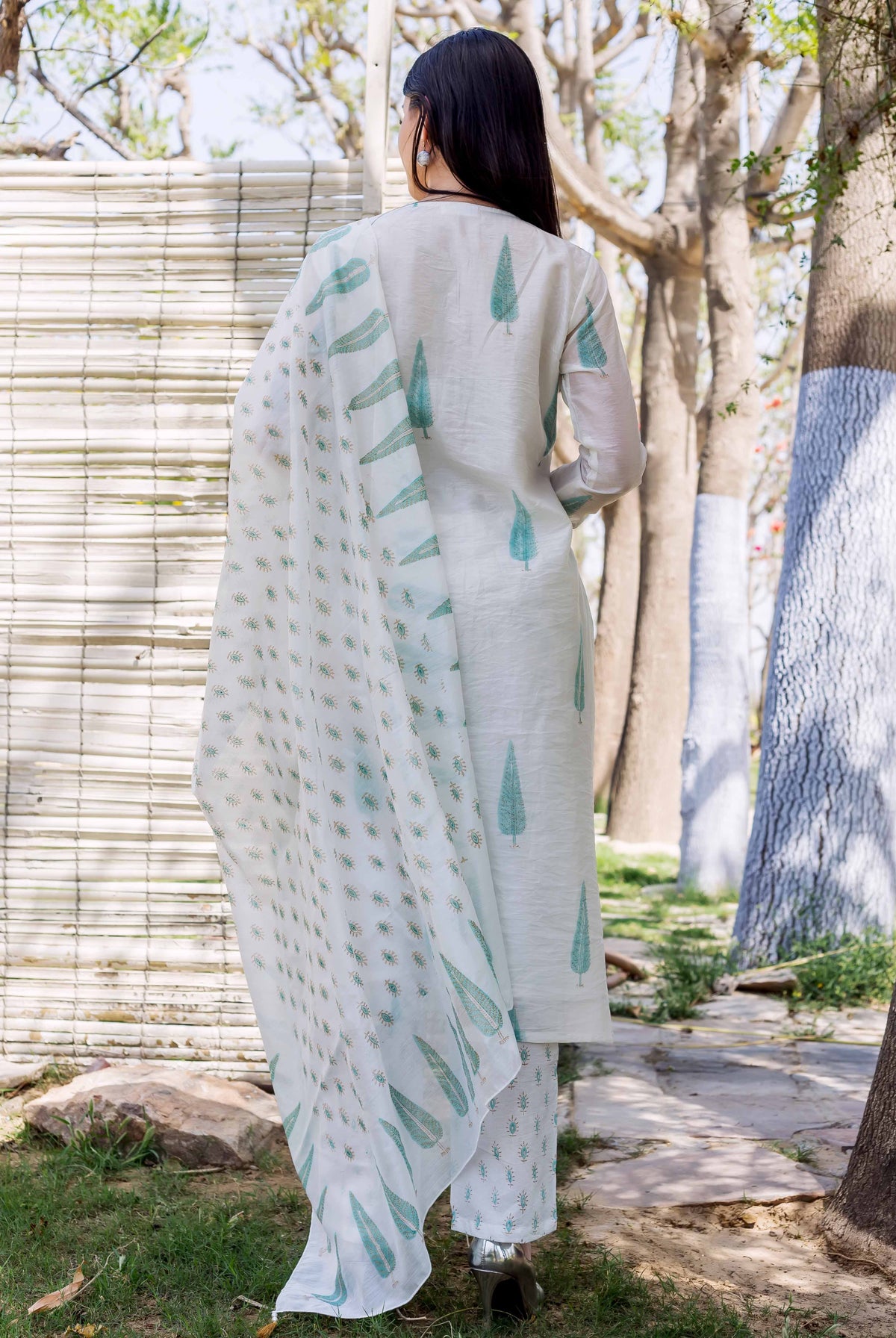A woman in a white and green hand-block-printed kurta with a matching dupatta.