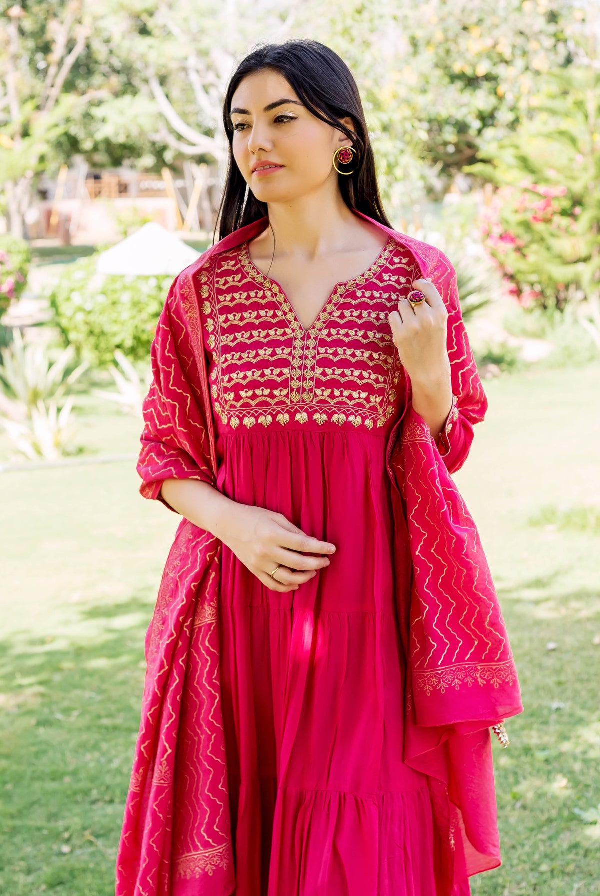 Model in raspberry red tiered dress with golden embroidered yoke and printed dupatta.