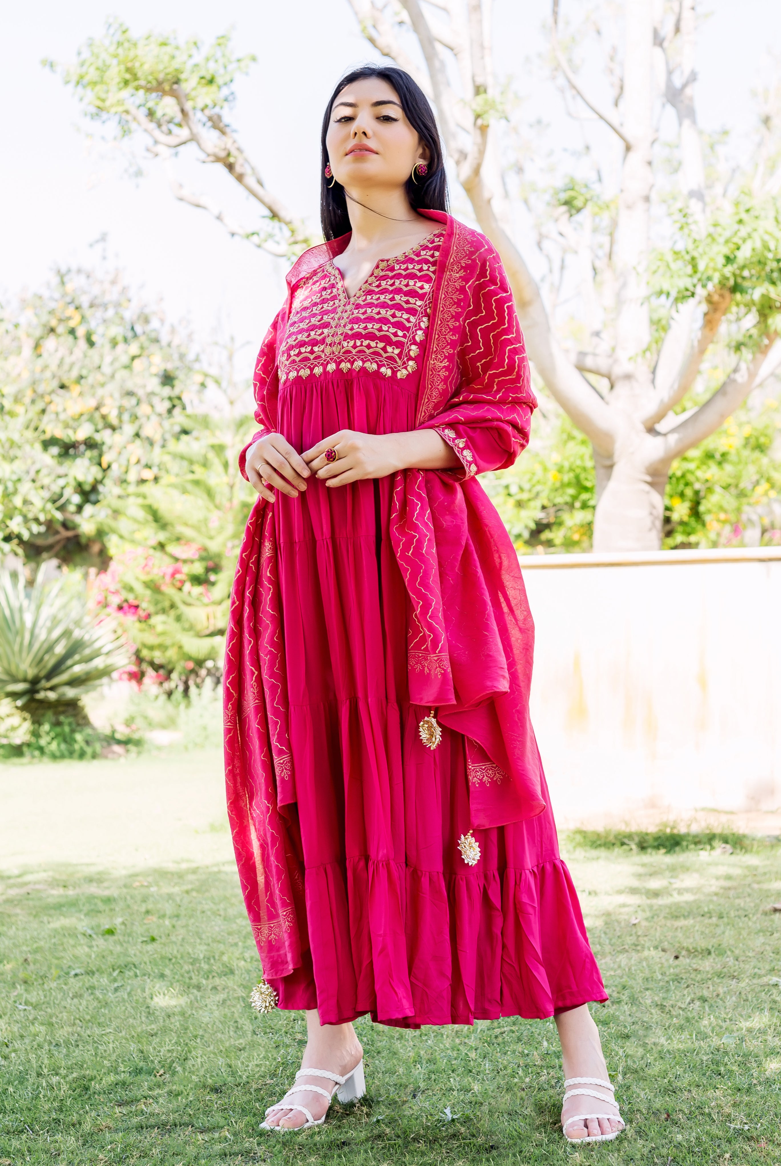 Full-length model in raspberry red tiered dress with gold embroidered yoke and geometric print.