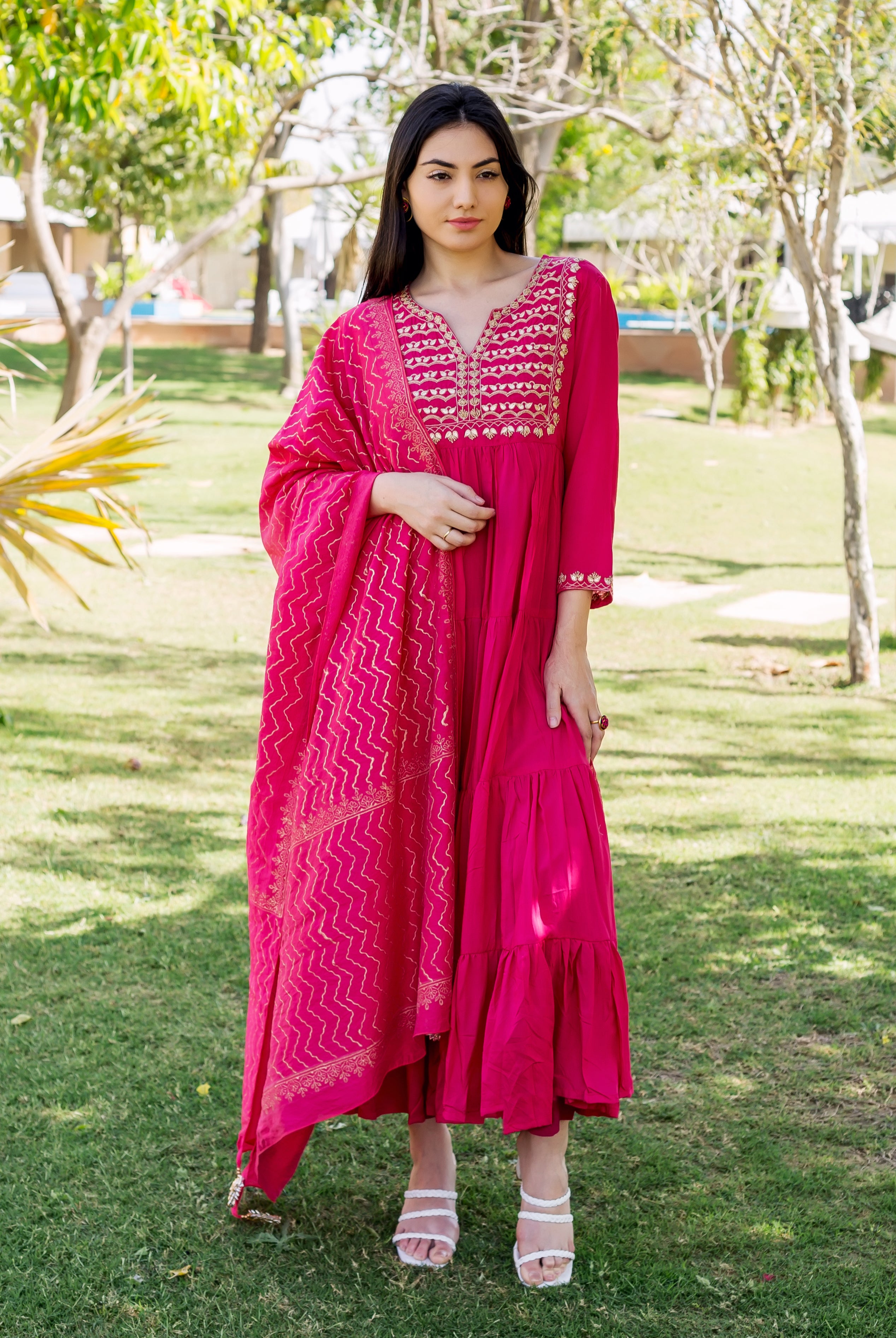 Model in a raspberry red tiered dress with gold embroidered yoke and zig-zag dupatta.