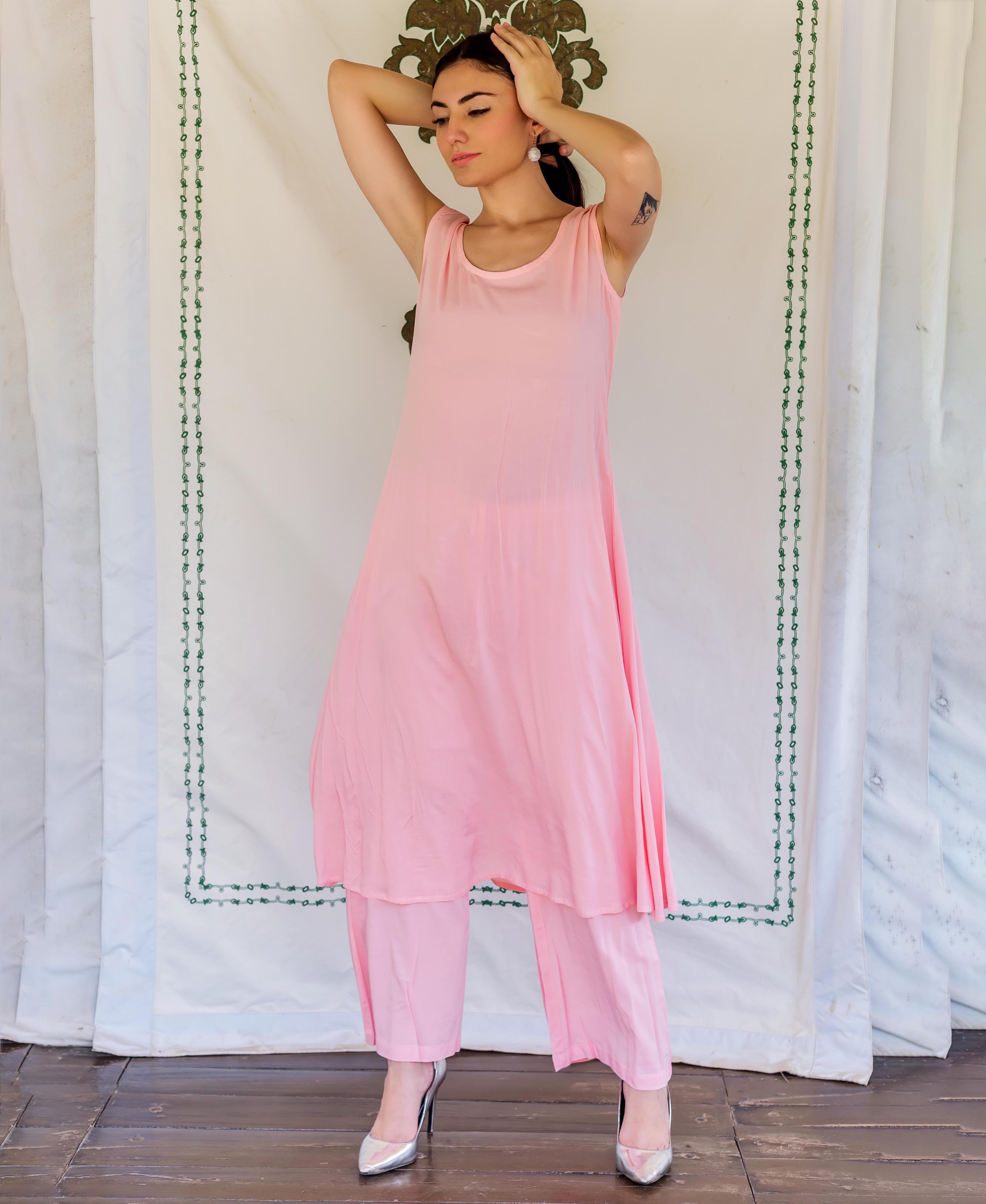 Front view of model wearing a sleeveless flamingo pink kurta and matching pants.