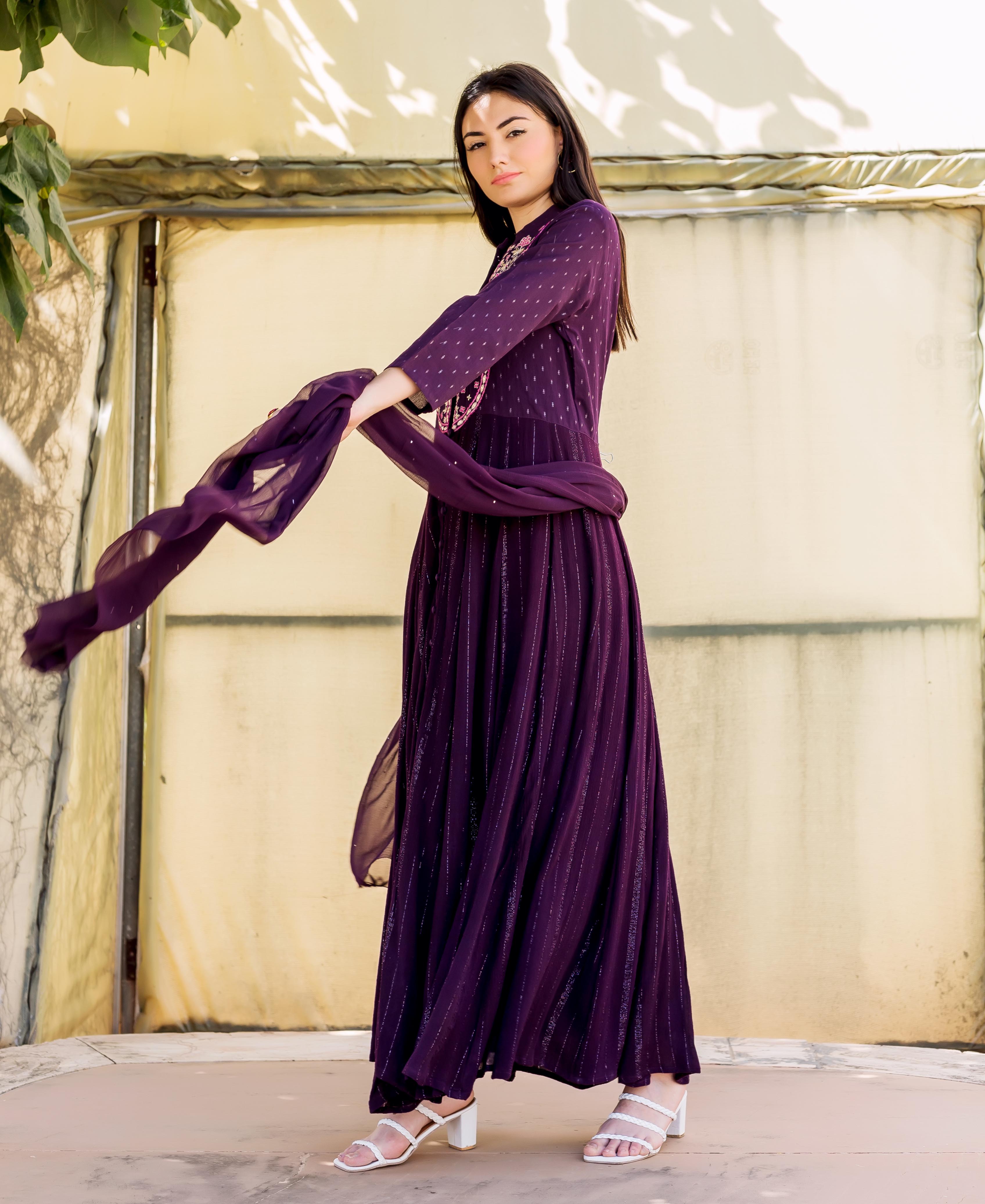 Model in full-length wine Lurex embroidered Anarkali with flowing purple dupatta.