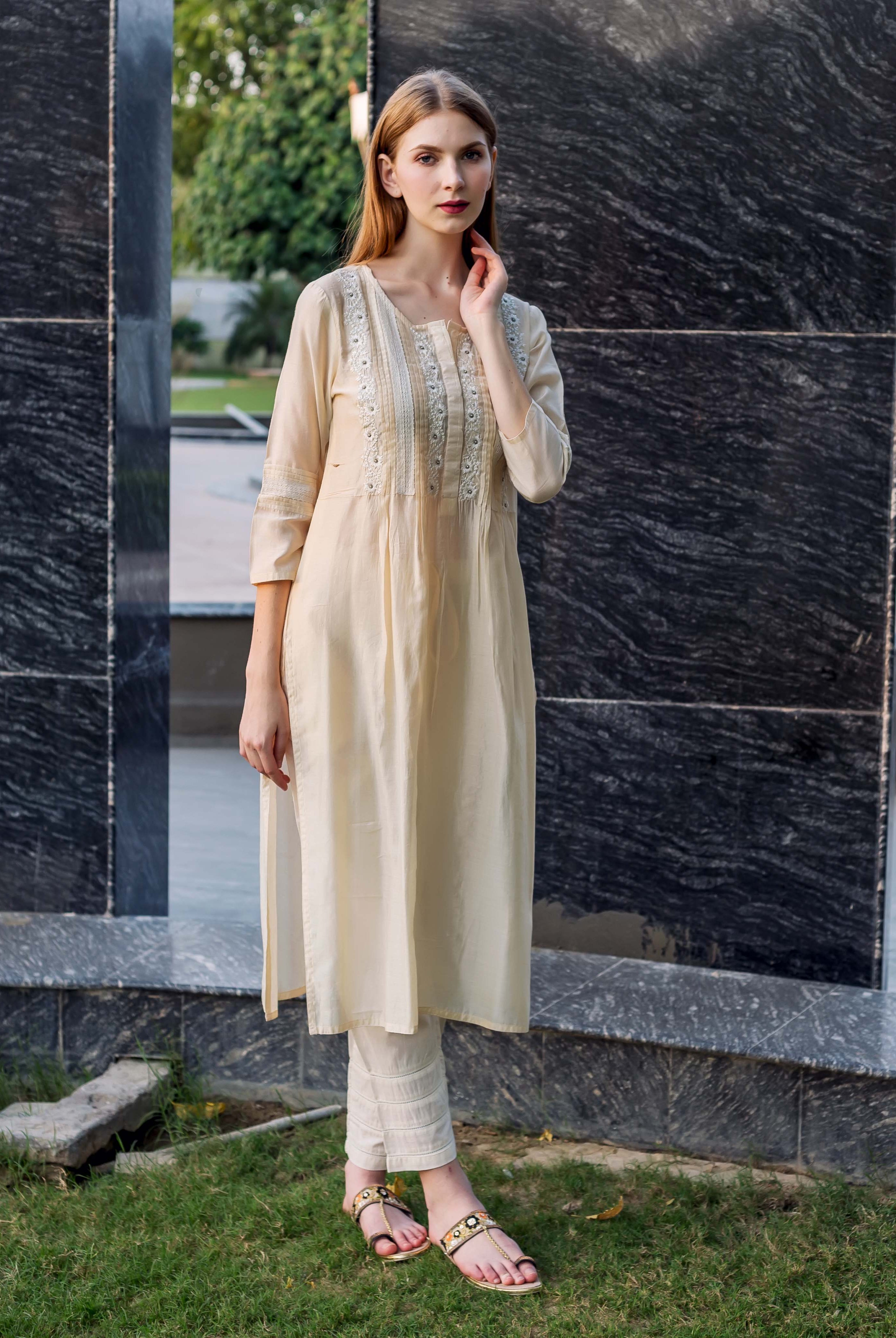 Full shot of model wearing off-white straight embroidered kurta with pintuck and lace details.